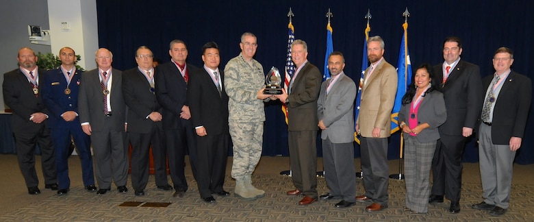 Gen. John E. Hyten , Air Force Space Command commander, presents the 2013 Chief of Staff Team Excellence award  to Air Force Space Command’s Space Training Evolution Plan Team for their Standard Space Trainer during an all-call at the Space and Missile Systems Center Nov.20, 2014, in California. The SST enabled an efficient and interchangeable space-operator training system throughout the Air Force. (U.S. Air Force photo) 