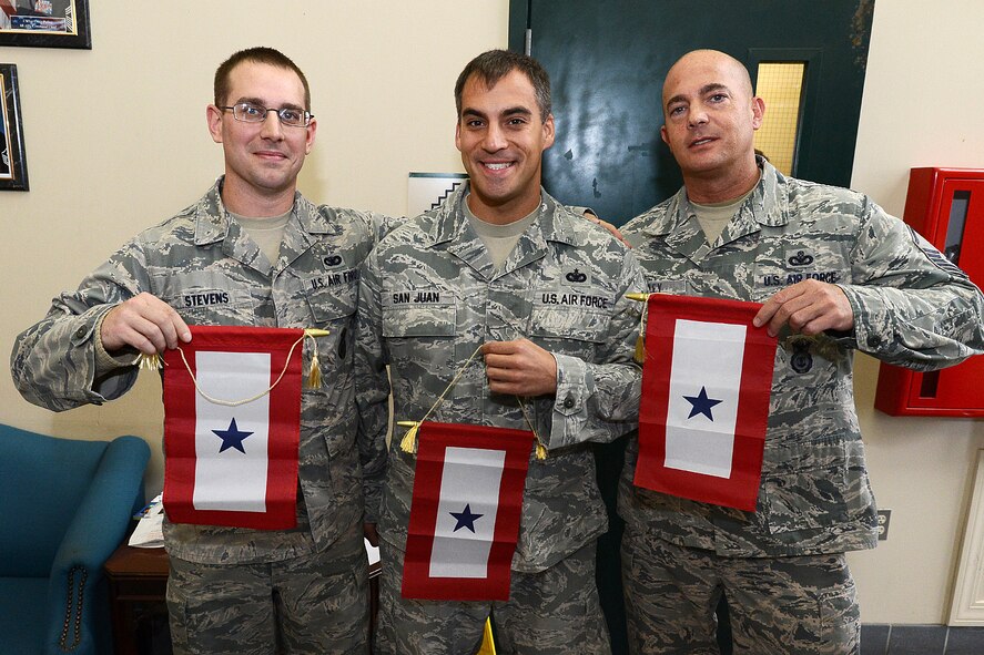 Senior Airman Robert Stevens, Tech. Sgt. Don San Juan and Master Sgt. Robert Cawley pose for a picture holding their Blue Star Flags during a ceremony at Building 1725, Jan. 12. The ceremony was to welcome home the Airmen, all security forces specialists, from an overseas deployment. The squadron has a tradition in which deploying personnel hang a Blue Star Flag on a wall in the building when they deploy and remove it when they return. (U.S. Air Force photo by Jerry Saslav)