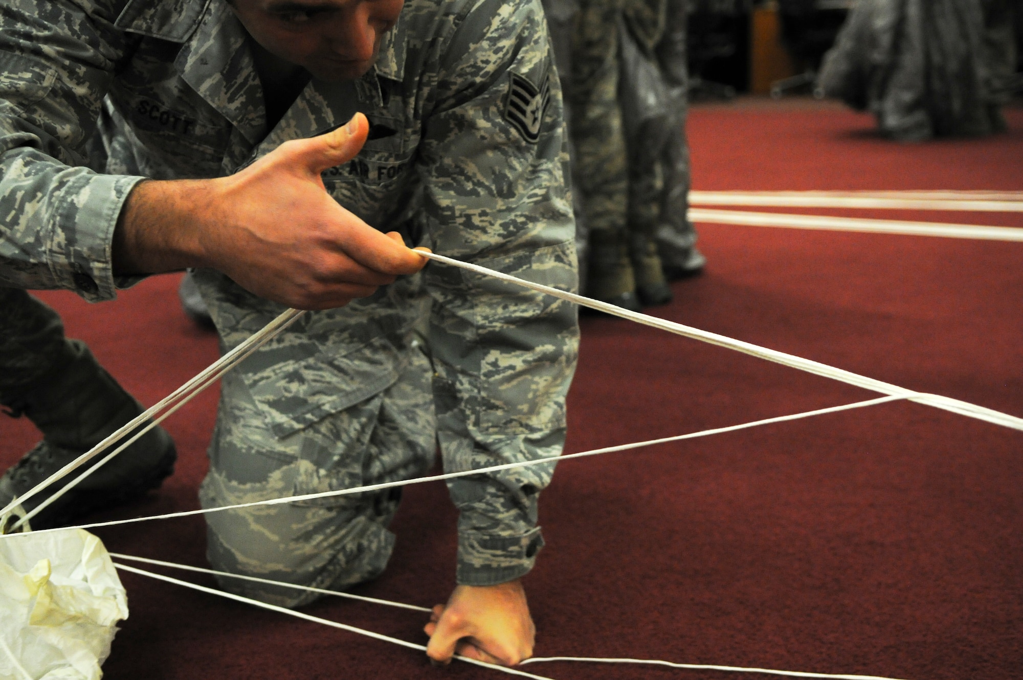 U.S. Air Force Staff Sgt. Clint Scott, 38th Rescue Squadron aircrew flight equipment assistant NCO in charge, checks for line continuity on a parachute Jan. 12, 2015, at Moody Air Force Base, Ga. Checking for line continuity ensures there are no twists and helps prevent malfunctions. (U.S. Air Force photo by Senior Airman Sandra Marrero/Released)
