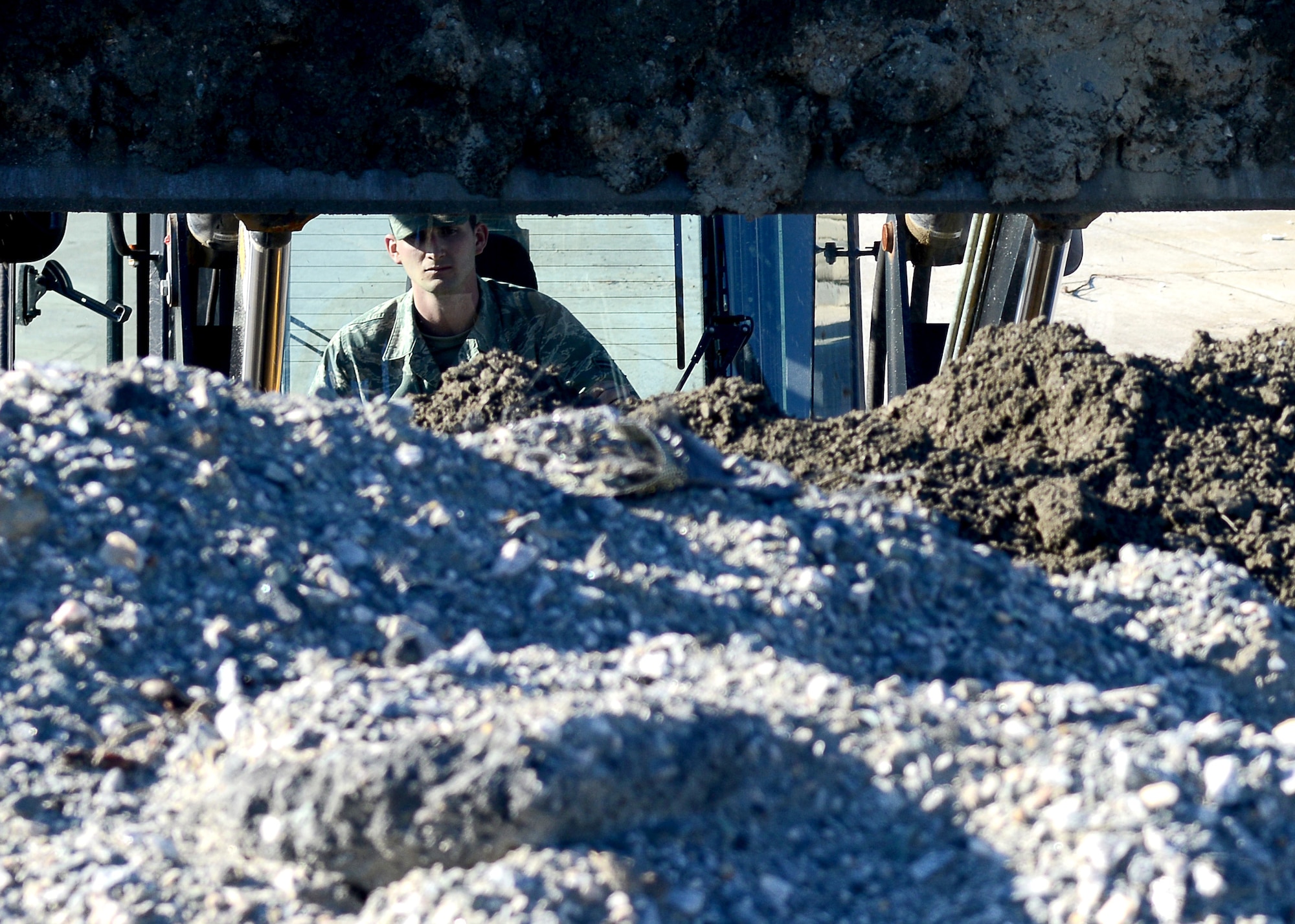 U.S. Air Force Airman 1st Class Brandon Ritenour, 633rd Civil Engineer Squadron heavy equipment operator, reaches for gravel using a loader at Langley Air Force Base, Va., Jan. 9, 2015. Ritenour and his team repair and maintain the flight line by removing debris and leveling the concrete’s surface. (U.S. Air Force photo by Airman 1st Class Devin Scott Michaels/Released)