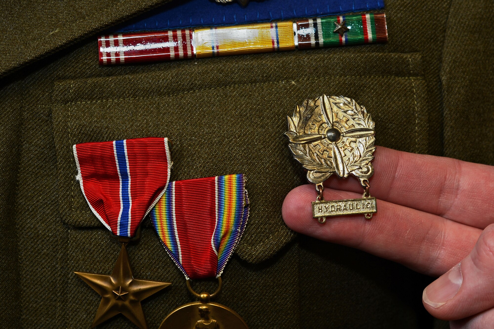 A U.S. Air Force Airman assigned to the 20th Maintenance Group, touches an original aircraft maintenance badge at Shaw Air Force Base, S.C., Jan. 9, 2015. Lt. Col. Kyle Clement, 20th MXG deputy commander, purchased this badge as a teenager, starting his life-long passion for collection Airman memorabilia. (U.S. Air Force photo by Senior Airman Jensen Stidham/Released) 