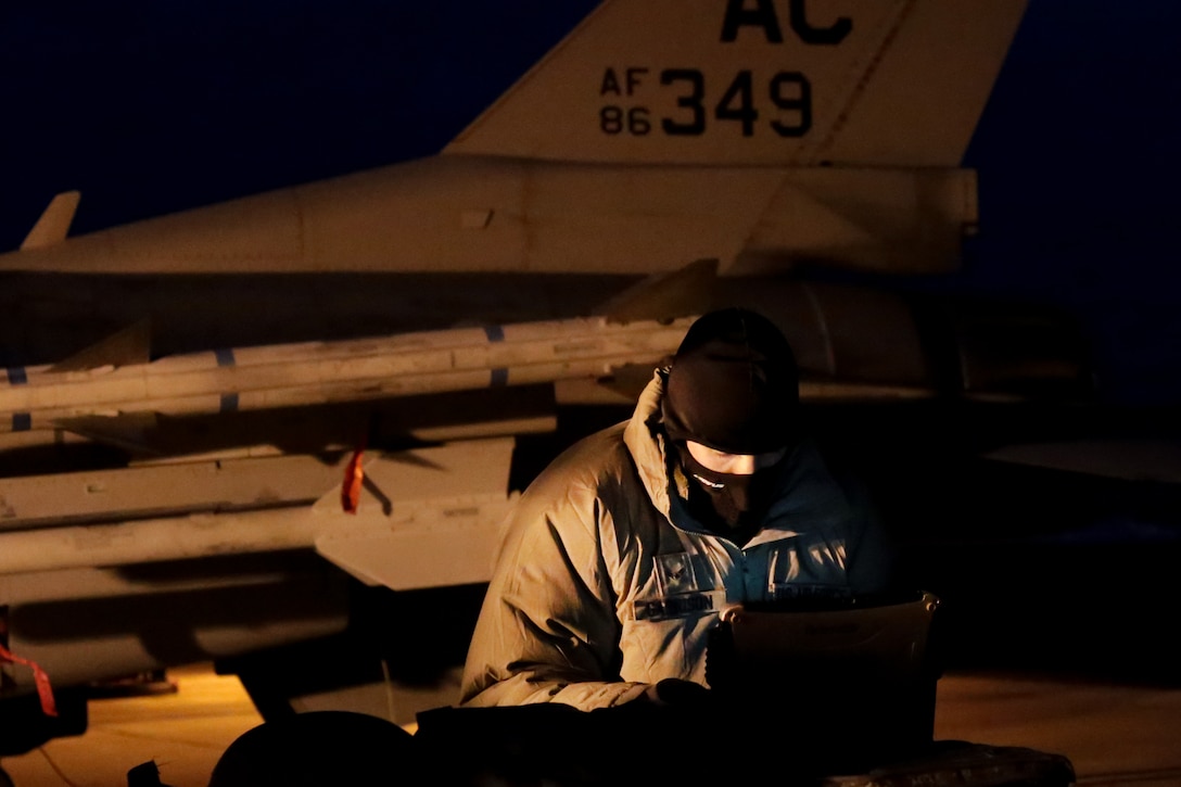 U.S. Air Force Airman 1st Class Christopher Garrison, an F-16 crew chief from the New Jersey Air National Guard's 177th Fighter Wing, goes over technical orders prior to a training mission early in the morning at Atlantic City Air National Guard Base, N.J., Jan. 9, 2015. Airmen from the 177th Fighter Wing took part in JAN ME EX 15-01, a mission employment exercise that tested the Wing's sortie generation capabilities. (U.S. Air National Guard photo by Tech. Sgt. Matt Hecht/Released) 