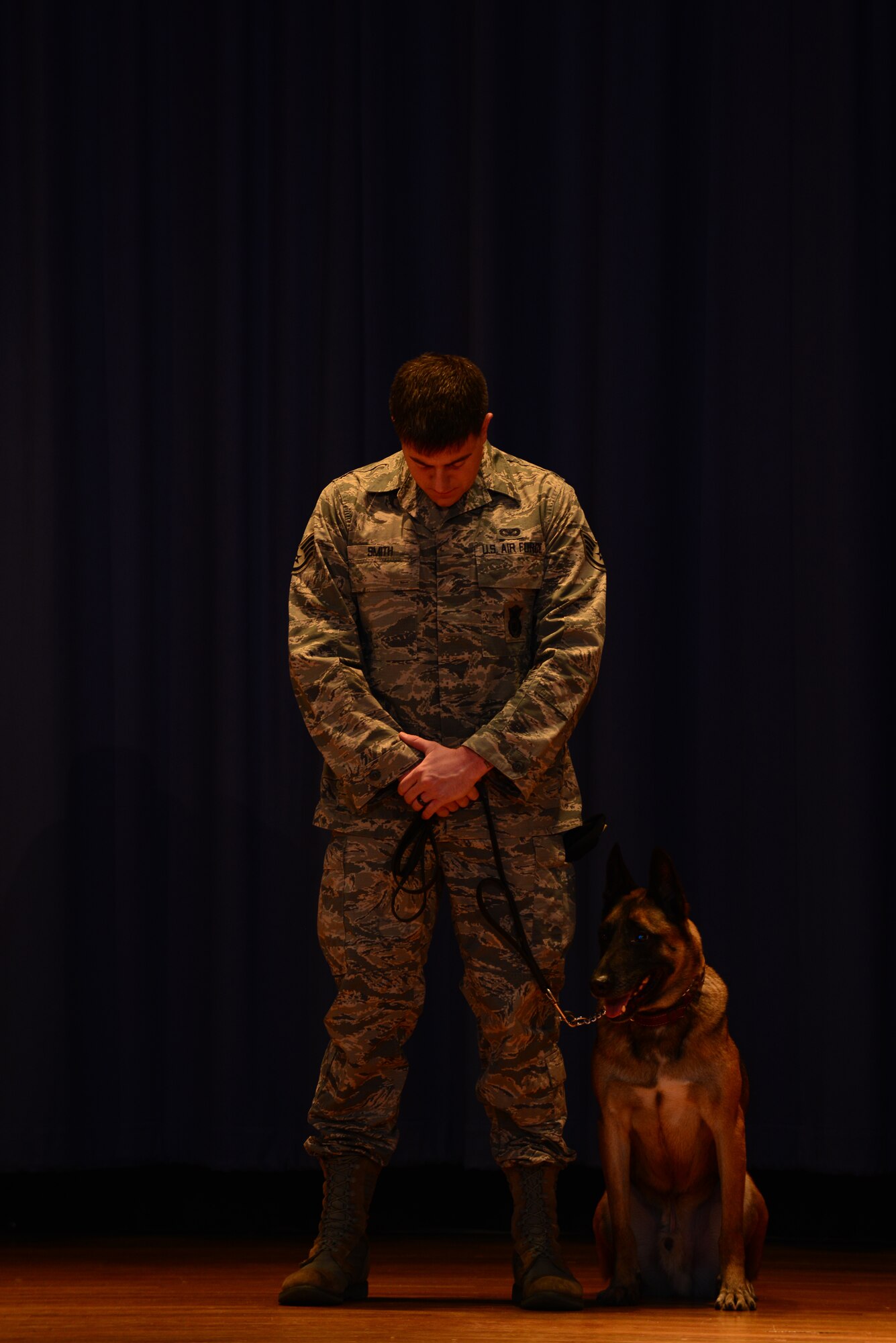 U.S. Air Force Staff Sgt. Brandon Smith, 633rd Security Forces Squadron Military Working Dog handler, and Max, 633rd SFS MWD, reflect on the memories they’ve shared with Erdo M614, former 633rd SFS MWD, during a memorial ceremony at Langley Air Force Base, Va., Jan. 8, 2015. During the ceremony, a member of the 633rd SFS MWD section recited the poem, “Guardians of the Night;” an ode to the dedication and sacrifices of MWDs. (U.S. Air Force photo by Staff Sgt. Natasha Stannard/Released)