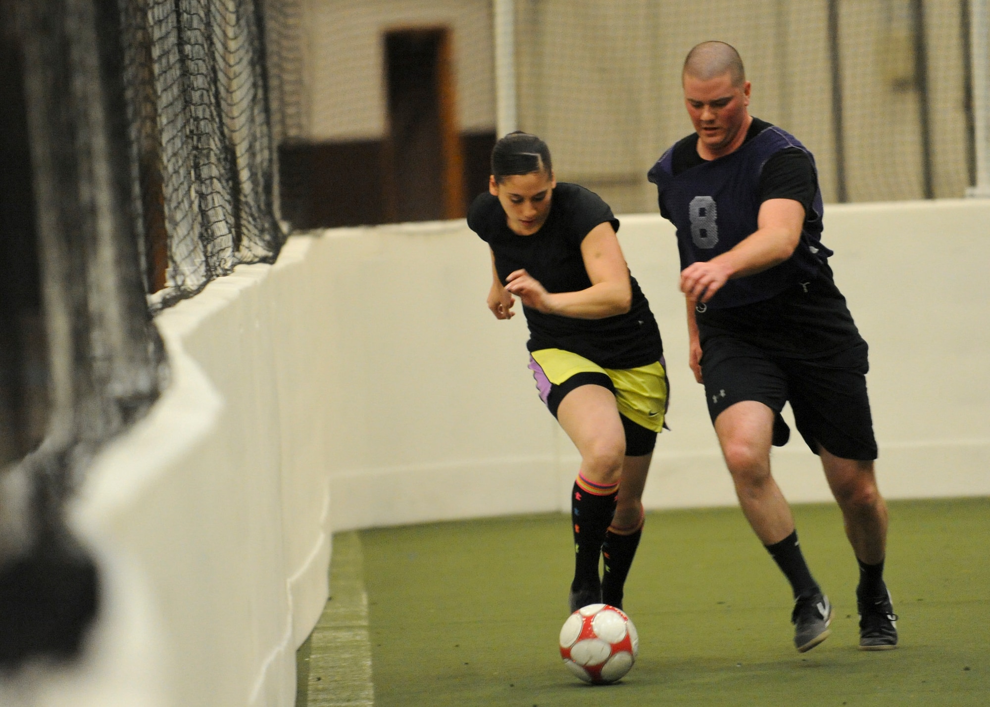 Airman 1st Class Alexandra Walsh, 28th Bomb Wing Judge Advocate civil law paralegal, maneuvers past an opponent from the 28th Logistics Readiness Squadron team during a soccer match inside the Pride Hangar at Ellsworth Air Force Base, S.D., Dec. 17, 2014. The 28th LRS team emerged victorious winning the match with a score of 10 to 1. (U.S. Air Force photo by Senior Airman Anania Tekurio/Released) 