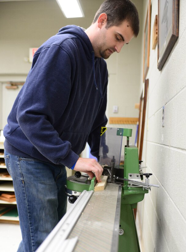 Joe Altergott, 28th Force Support Squadron arts and crafts and marketing visual information specialist, cuts wood for a frame in the Arts and Crafts Center on Ellsworth Air Force Base, S.D., Dec. 18, 2014. The Arts and Crafts Center is able to create a wide variety of custom items for almost any occasion, open from Monday through Friday from 9 a.m. to 6 p.m. (U.S. Air Force photo by Senior Airman Zachary Hada/Released)