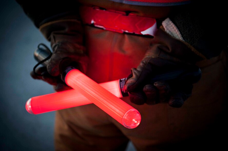 Senior Airman Taylor Lancaster, 5th Aircraft Maintenance Squadron aircraft crew chief, holds “lollipops” behind his back on Minot Air Force Base, N.D., Jan. 9, 2014. Lancaster uses the light sticks to help guide the jet out of its spot to taxi on the runway. (U.S. Air Force photo/Airman 1st Class Sahara L. Fales)