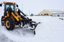 A member of the 341st Civil Engineer Squadron clears snow with a heavy duty tractor to ensure roadways and facility entrances are safe for vehicles on Malmstrom Air Force Base Jan. 7. Civil engineer members play a key role in winter safety measures and snow removal for more than 300 on-base facilities. (U.S. Air Force photo/Airman 1st Class Collin Schmidt)  