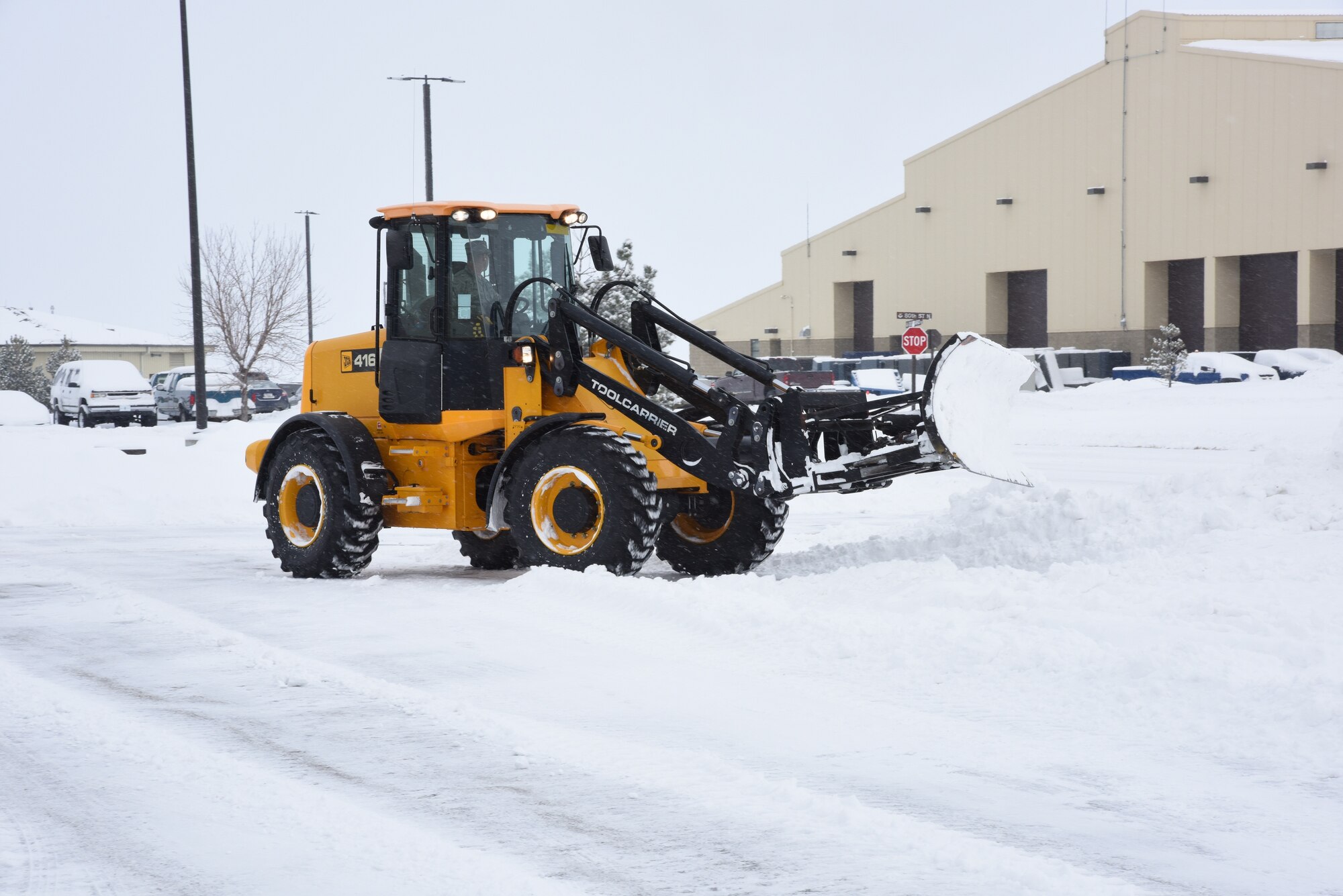 A member of the 341st Civil Engineer Squadron clears snow with a heavy duty tractor to ensure roadways and facility entrances are safe for vehicles on Malmstrom Air Force Base Jan. 7. During the winter season, CES members move tons of snow to keep Malmstrom’s daily operations running smoothly. (U.S. Air Force photo/Airman 1st Class Collin Schmidt)  