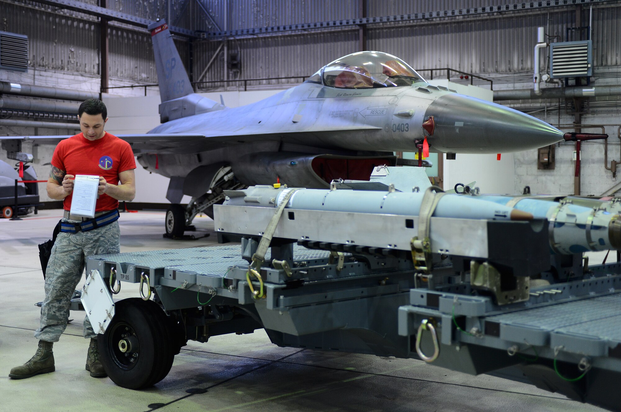 U.S. Air Force Staff Sgt. Michael Nichter, 52nd Aircraft Maintenance Squadron weapons load crew chief, goes through a checklist next to an F-16 Fighting Falcon Fighter aircraft during a weapons load competition in Hangar 1 at Spangdahlem Air Base, Germany, Jan. 9, 2015. Nichter was a part of the load team that won the competition last year. (U.S. Air Force photo by Airman 1st Class Luke Kitterman/Released) 