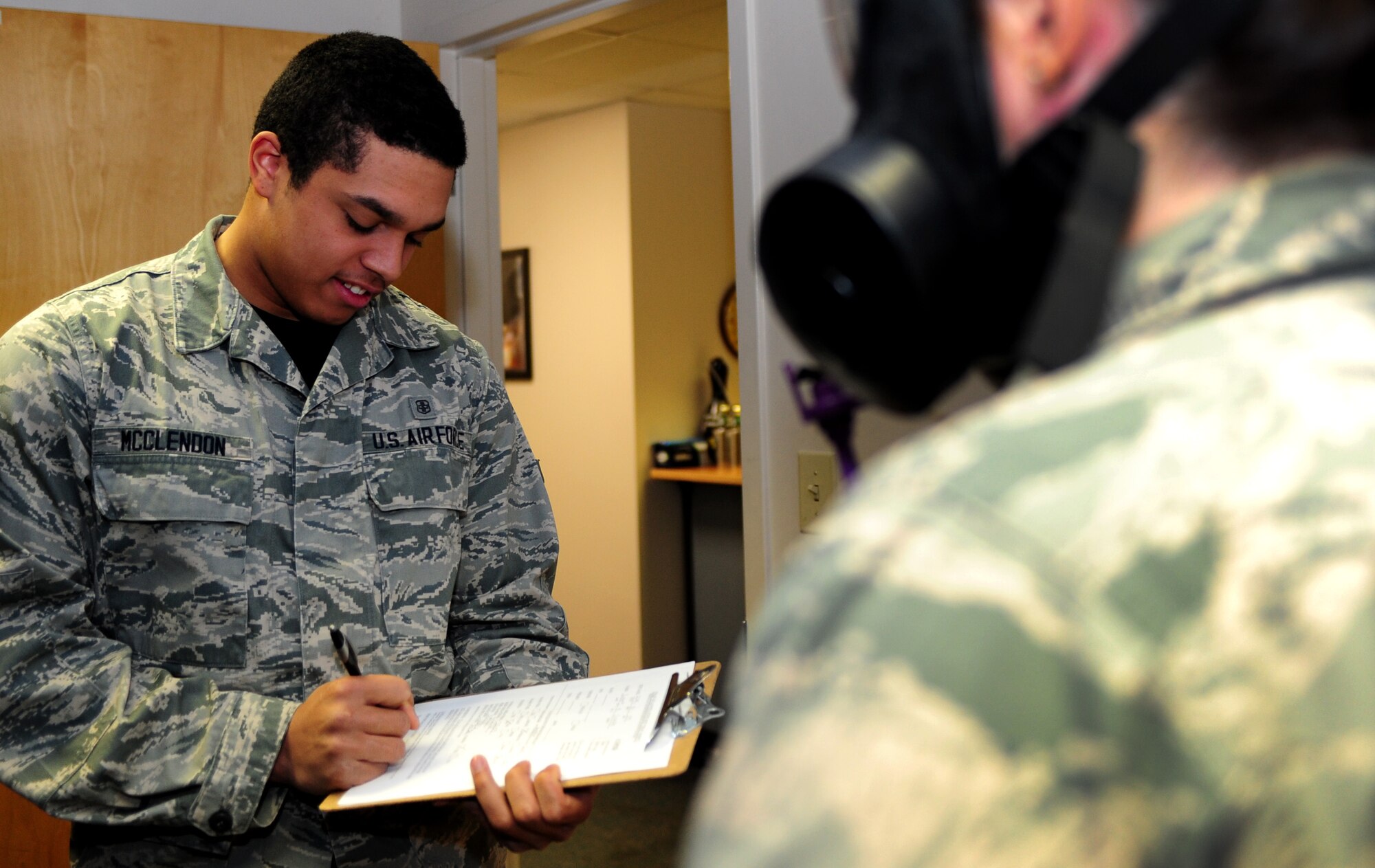 U.S. Air Force Airman 1st Class Alex McClendon, 633rd Aerospace Medicine Squadron bioenvironmental engineer technician, performs a gas mask fit test on Senior Airman Sarah Lowry, 633rd AMDS bioenvironmental engineer technician at Langley Air Force, Va., Jan. 9, 2015. During the test, Lowry looked up and down and side to side to help ensure masks fits properly and to pass the fit test.  (U.S. Air Force photo by Airman 1st Class Areca T. Wilson/Released) 