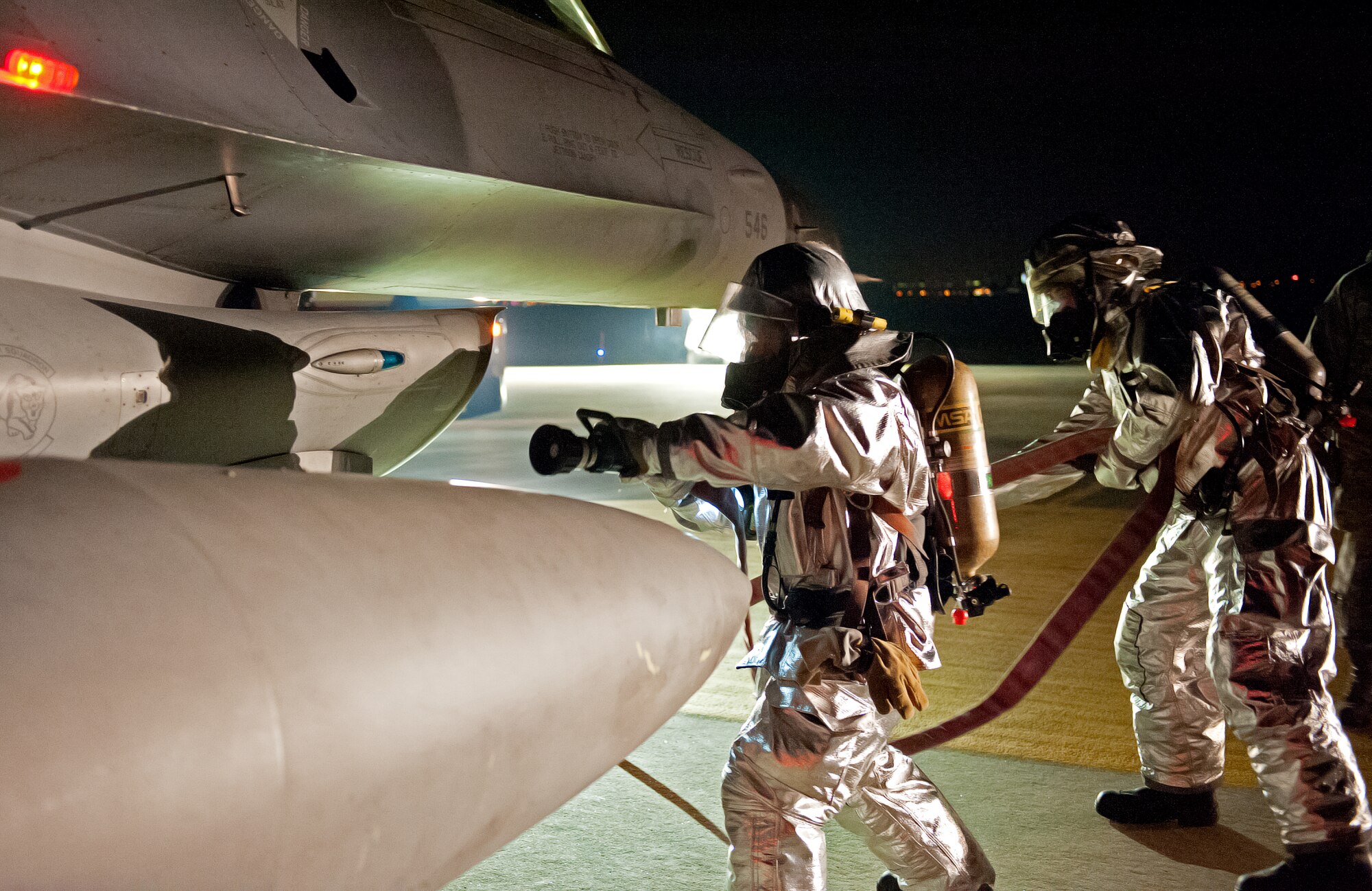 First responders from the 8th Civil Engineer Squadron fire department, simulate hosing down an F-16 Fighting Falcon during an emergency management exercise at Kunsan Air Base, Republic of Korea, Jan. 12, 2015. The EME tested the Wolf Pack’s ability to quickly respond to an aircraft accident while providing realistic training. (U.S. Air Force photo by Senior Airman Divine Cox/Released)