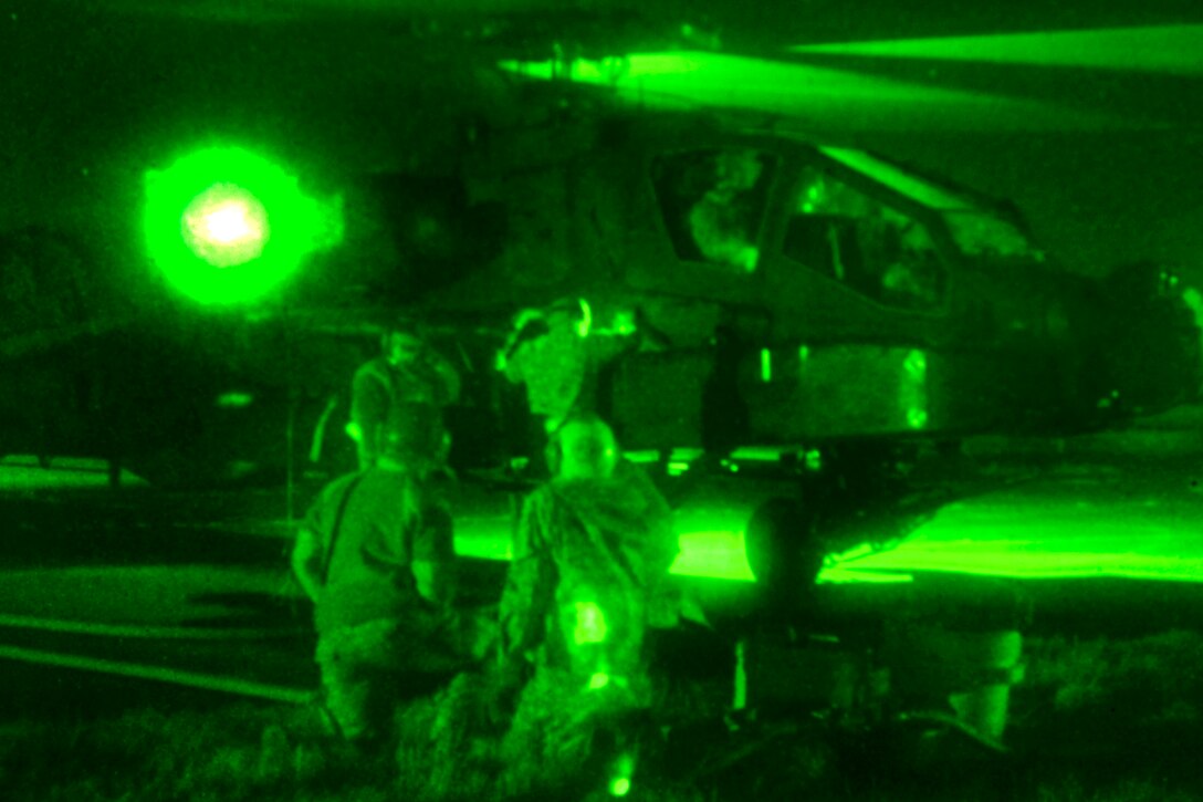 As seen through a night-vision device, soldiers refuel AH-64 Apache helicopters at a forward arming and refueling point during night interdiction attack training with AH-64 Apache helicopters on McEntire Joint National Guard Base in Eastover, S.C., Jan. 10, 2015.