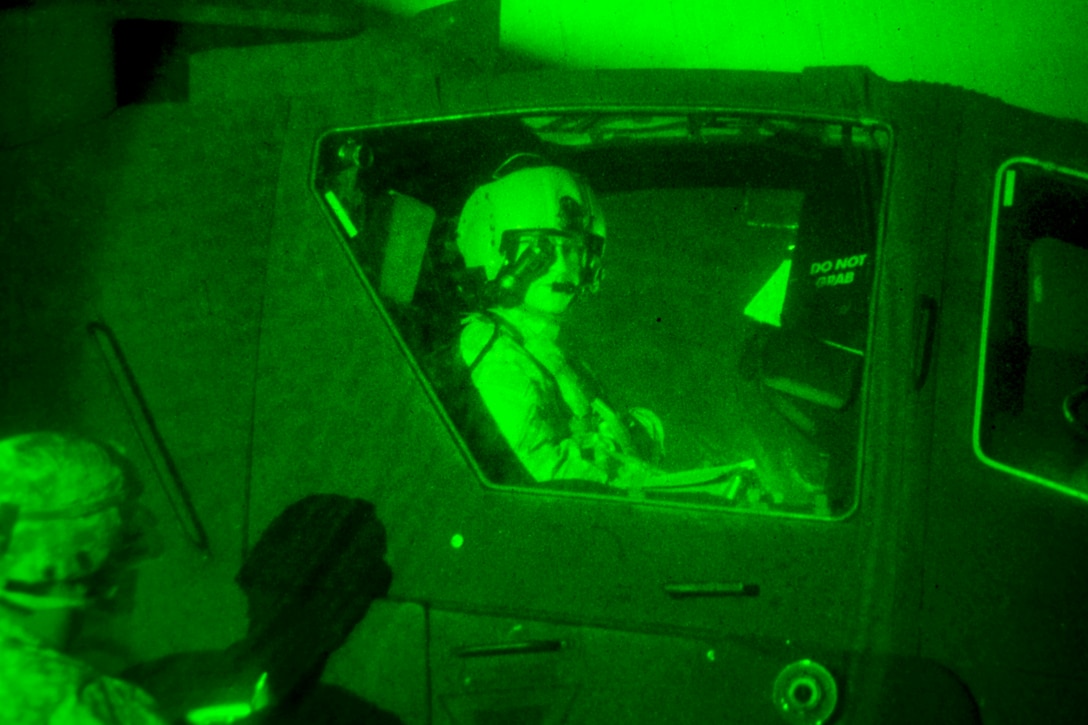 As seen through a night-vision device, a soldier communicates with the pilot before taking off after refueling his AH-64 Apache helicopter at a forward arming and refueling point as part of a battalion exercise on McEntire Joint National Guard Base in Eastover, S.C., Jan. 10, 2015.