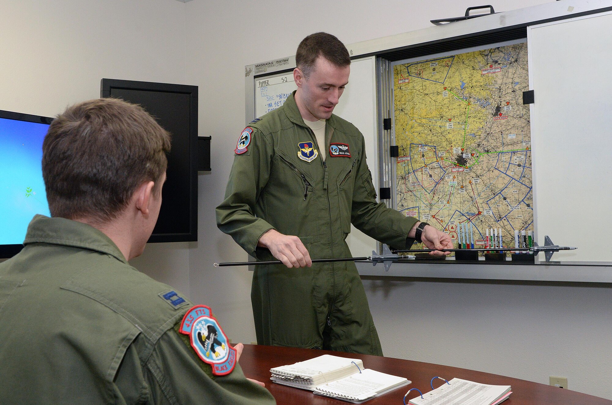 Capt. Sean Jones, 435th Fighter Training Squadron, demonstrates basic fighter maneuvers to Capt. Christopher Bernardo prior to a morning training flight Jan. 8, 2015, at Joint Base San Antonio-Randolph. (U.S. Air Force photo by Johnny Saldivar)