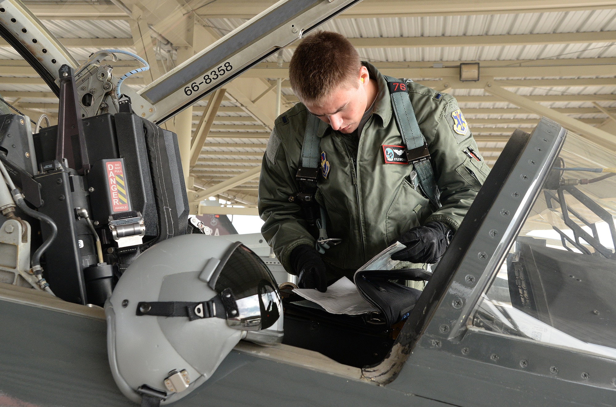 First Lt. Kyle Brown, 435th Fighter Training Squadron, inspects aircraft logs during a pre-flight inspection prior to a morning training flight Jan. 8, 2015, at Joint Base San Antonio-Randolph. During preflight inspections, aircrew members examine the exterior and interior of aircraft, checking for discrepancies and ensuring serviceability. (U.S. Air Force photo by Johnny Saldivar)