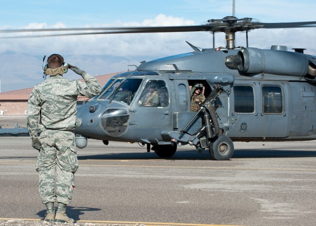 Airman 1st Class Hunter Foust, 823rd Maintenance Squadron HH-60G Pave Hawk crew chief, salutes the crew of an HH-60 as it taxis for takeoff at Nellis Air Force Base, Nev., Jan. 12, 2015. The 823rd MXS is responsible for planning, scheduling and directing both scheduled and unscheduled maintenance on HH-60 helicopters to maintain a mission ready status. (U.S. Air Force photo by Senior Airman Thomas Spangler)