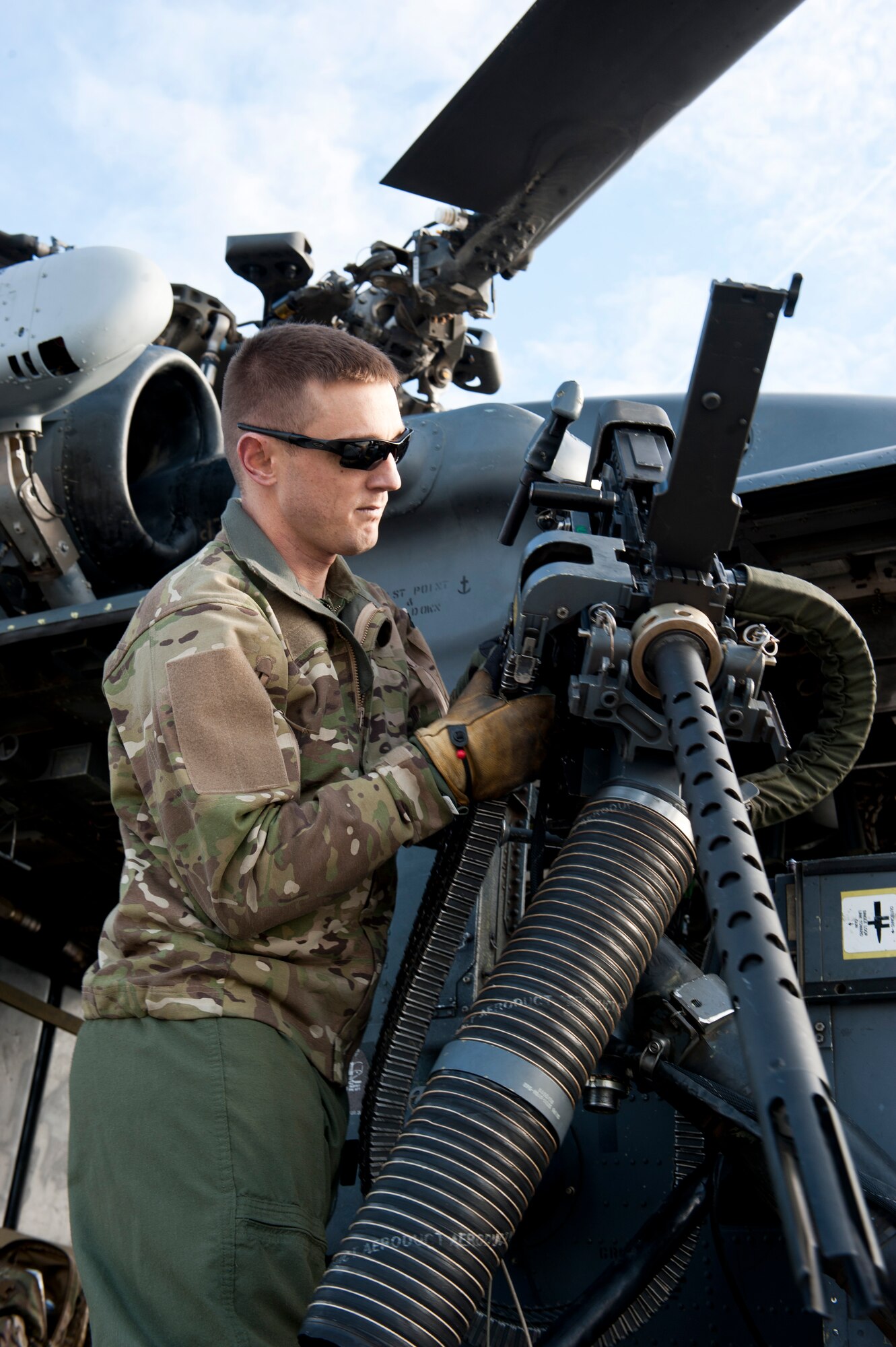 Tech. Sgt. Alex Rhynard, 66th Rescue Squadron special missions aviator evaluator, prepares a .50-caliber machine gun on an HH-60G Pave Hawk for a training exercise at Nellis Air Force Base, Nev., Jan. 12, 2015. Special missions aviators are required to man the weapon, scan for enemies and perform maintenance on the weapon if it malfunctions. (U.S. Air Force photo by Senior Airman Thomas Spangler)