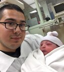Senior Airman Rolando Alvarado, 9th Force Support Squadron force management technician, hold his newborn child. (Courtesy photo)