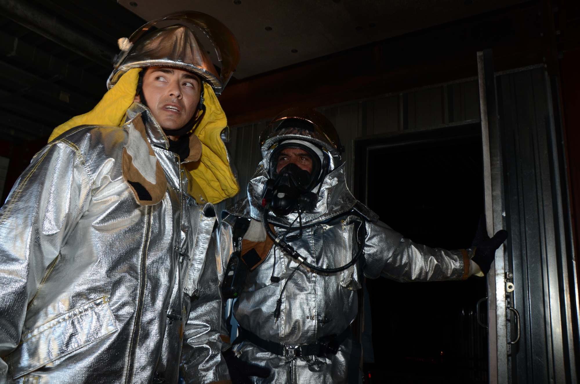 Tech. Sgt. Kaweo Andreas-Feeney, left, safety officer, and  Tech. Sgt. Kaohilii Romualdo, right, the assistant chief of training, both reservists with the 624th Civil Engineering Squadron, wait at the entrance to a live-fire burn room for the next team of firefighters to put out a simulated a kitchen fire fueled by propane gas. As civilians, Romualdo works fulltime for the Hawai'i State Fire Department and Andreas-Feeney for the City and County of the Honolulu Fire Department.(U.S. Air Force photo by Tech. Sgt. Phyllis Keith)