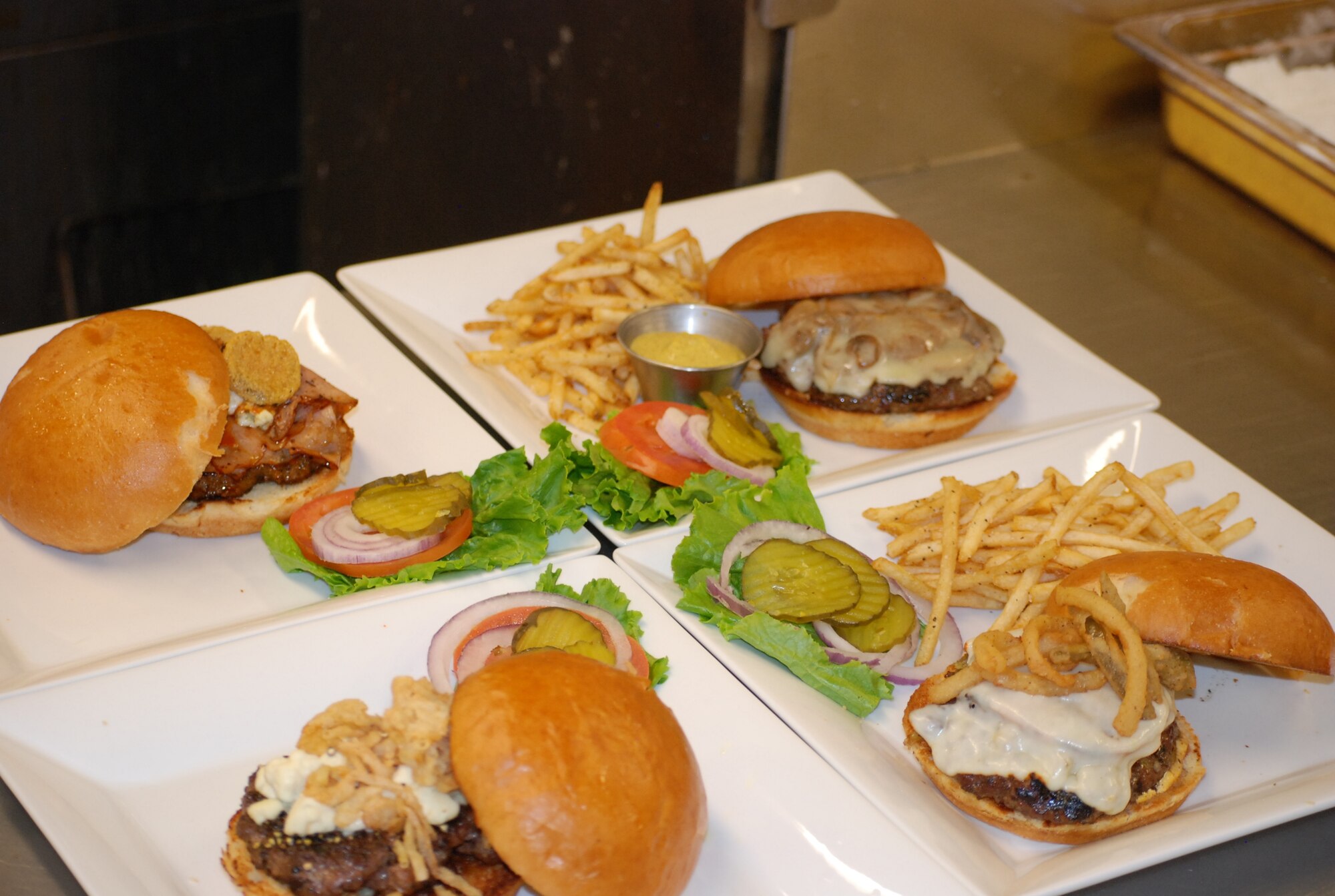 PETERSON AIR FORCE BASE, Colo. – Pictured are four of the new pub-style burgers available at the Club. Clockwise from top left: Club Big Boy with buffalo sauce, bleu cheese, grilled ham and fried pickles; Bristol Lab Chop House with grilled onions and mushrooms infused with Bristol Laughing Lab Scottish ale topped with provolone cheese; Cracked peppercorn and bleu cheese; and the Zamora with muenster cheese, green chiles, fried Texas toothpicks and a sriracha avocado aoli. Two other burgers, the 50-50 bacon burger and the teriyaki pineapple turkey burger are also available. (U.S. Air Force photo by Dave Smith)
 
