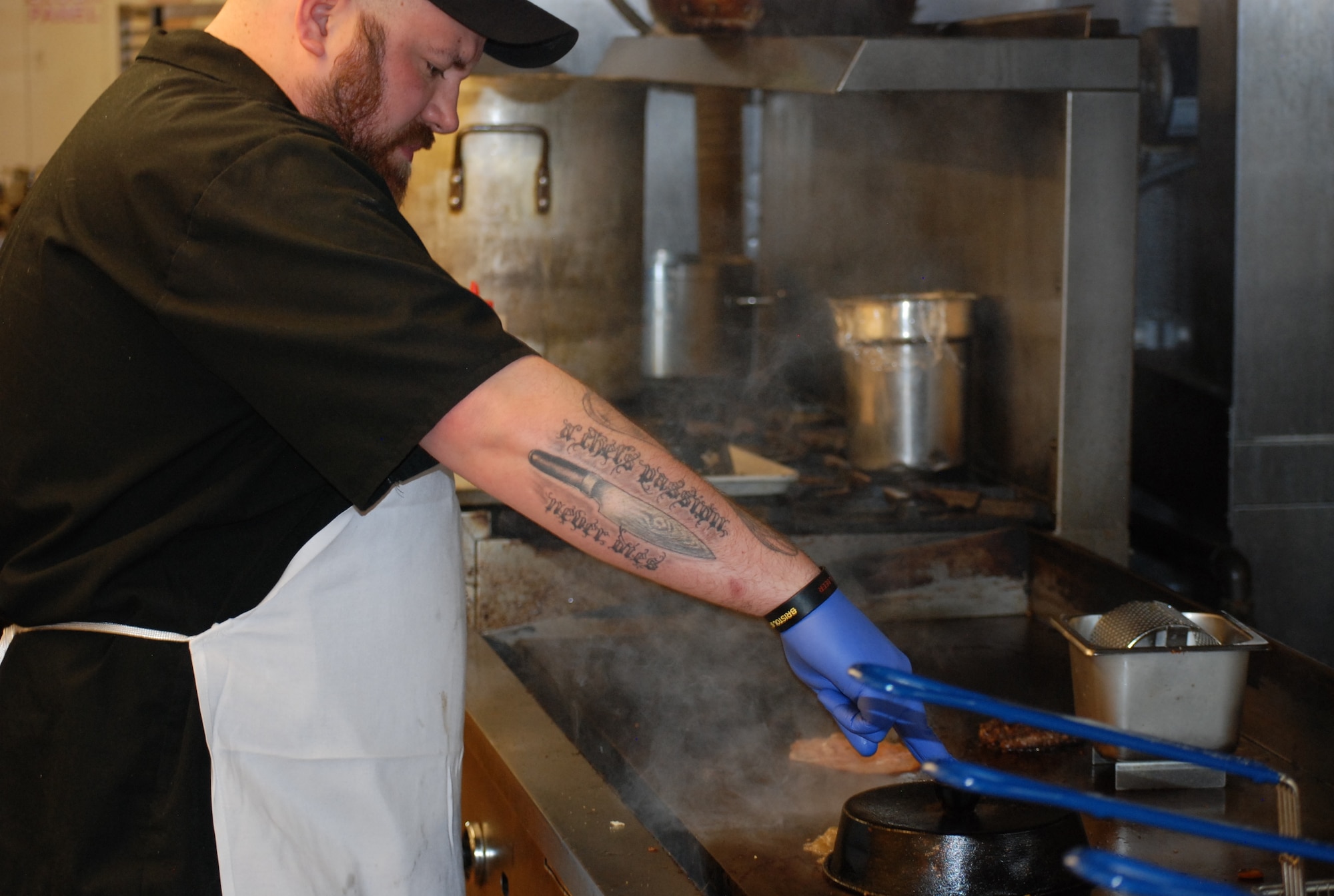 PETERSON AIR FORCE BASE, Colo. -- Club sous chef Kirk Dunning works the flat top finishing handmade hamburger patties in the Club's kitchen. The patties are the star attraction on one of six gourmet pub-style burgers now available. Other menu changes like pizza delivered on base and smoked barbecue food are other changes expected for 2015. (U.S. Air Force photo by Dave Smith)
 
