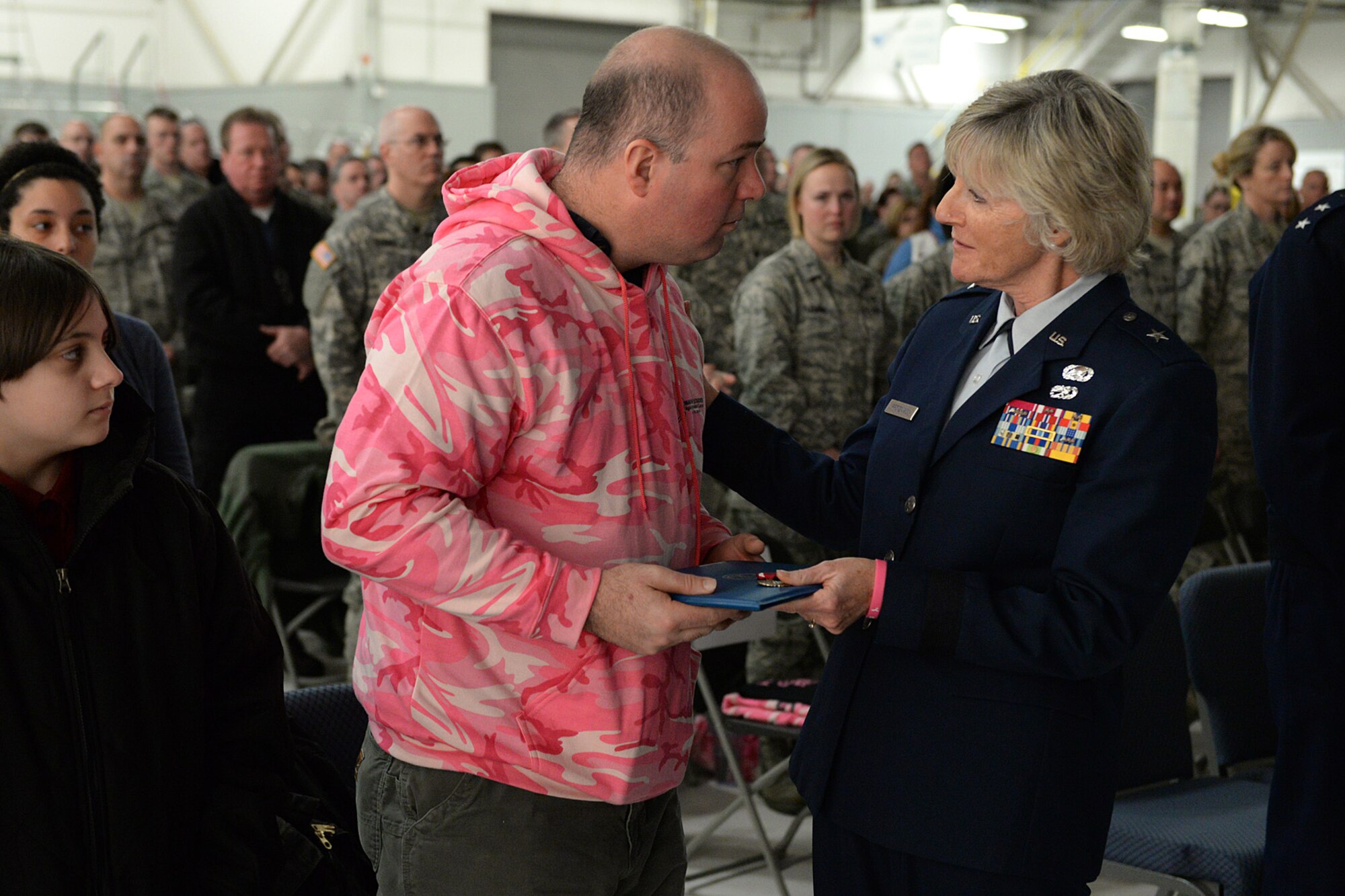 Brig. Gen. Carolyn J. Protzmann, N.H. Air National Guard commander, presents Shawn Riley the Legion of Merit Medal during a posthumous retirement ceremony for his wife, Lt. Col. Stephanie Riley, in Hangar 254, Jan. 10. Riley, who passed away Dec. 29 at the age of 47, was an occupational health nurse for the N.H. National Guard assigned to Joint Force Headquarters in Concord. (U.S. Air National Guard photo by Tech. Sgt. Mark Wyatt)