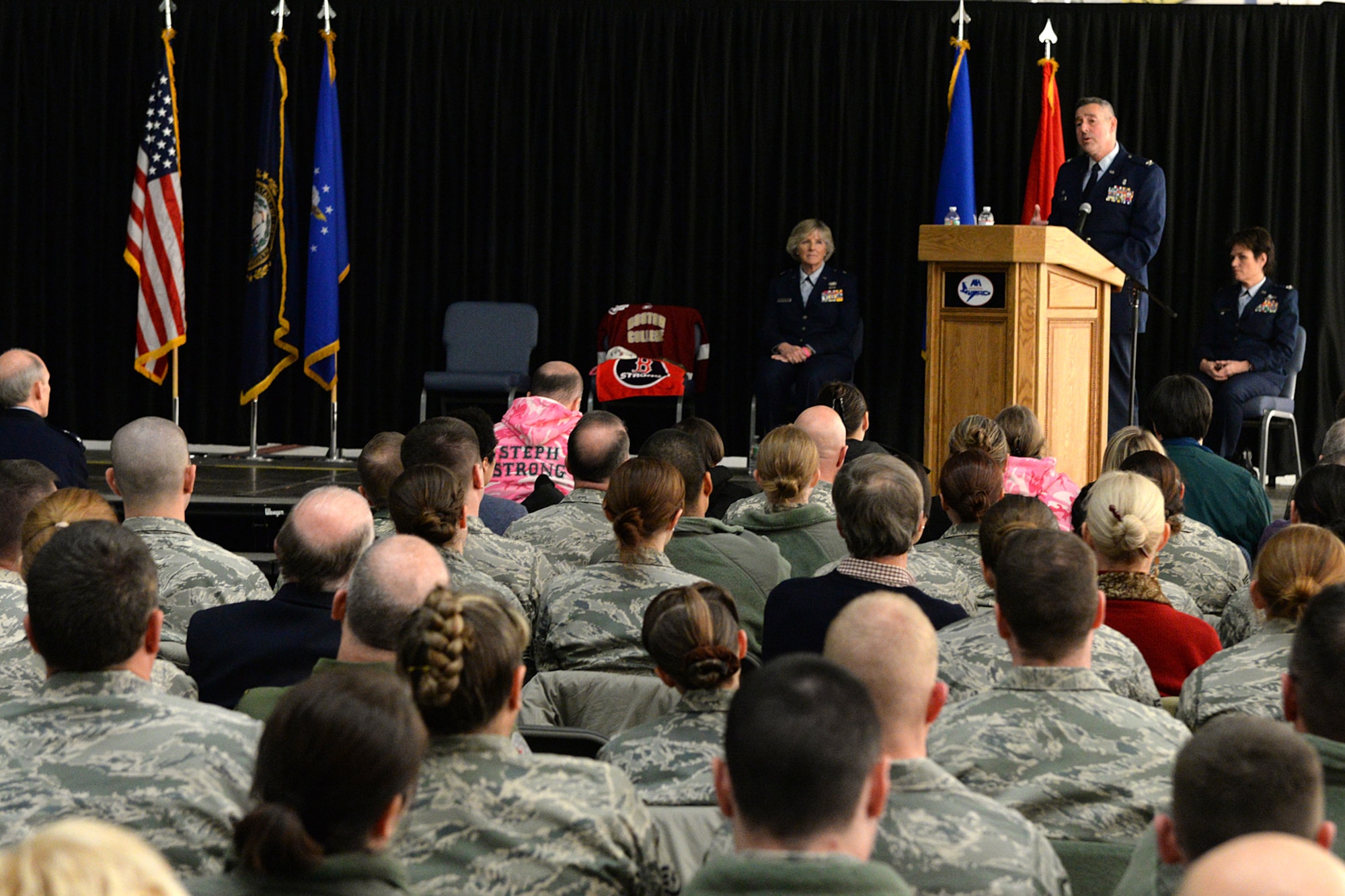 Col. Paul N. Loiselle, 157th Mission Support Group commander, speaks at the podium during a posthumous retirement ceremony for Lt. Col. Stephanie Riley on base Jan. 10, while Brig. Gen. Carolyn Protzmann, N.H. Air National Guard commander, listens. Loiselle, former commander of the 157th Medical Squadron, commanded the organization when Riley who was a nurse at the clinic. (U.S. Air National Guard photo by Tech. Sgt. Mark Wyatt)