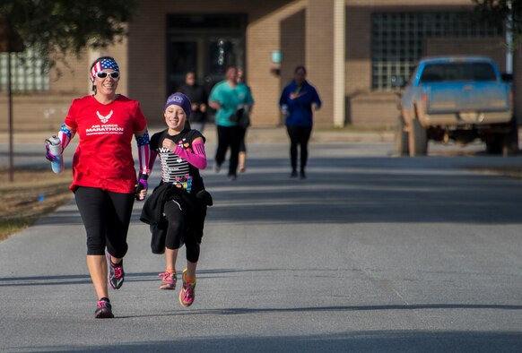 Master Sgt. Gloria Bermudezbly, Air Force Special Operations Command, helps a young competitor to the finish line during the Resolution 5k run Jan. 10 at Duke Field, Fla.  The proceeds benefit the Senior Airman Josh Santos Memorial.  More than 50 people participated.  (U.S. Air Force photo/Tech. Sgt. Jasmin Taylor)