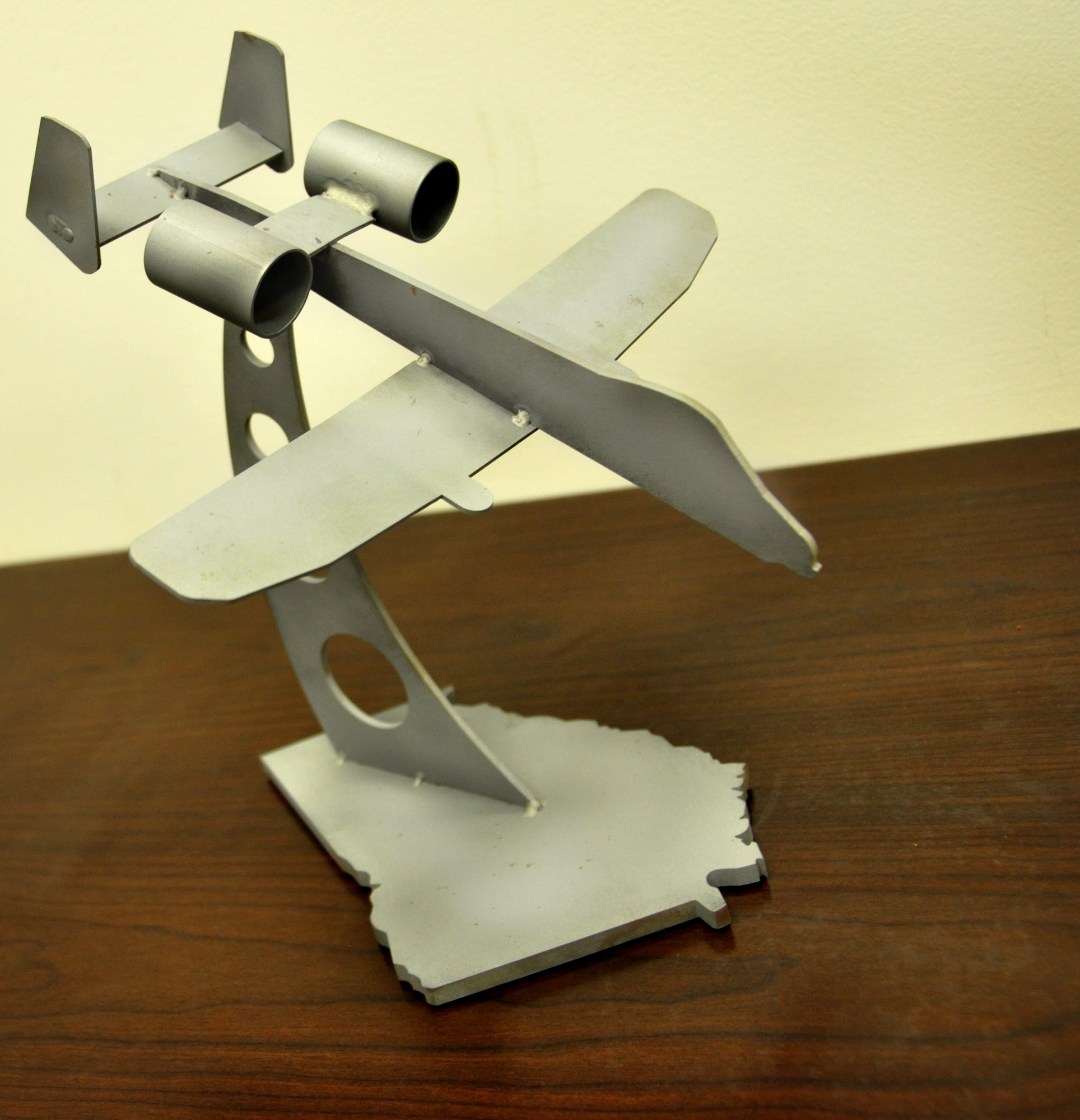 An A-10 Thunderbolt II model hand-welded by Col. James Travis and Master Sgt. Kristopher Prouty sits on the commander’s desk at Moody AFB, Ga. The base, cut by Prouty, is in the shape of the state of Georgia. (Air Force photo by Tech. Sgt. Emily F. Alley)