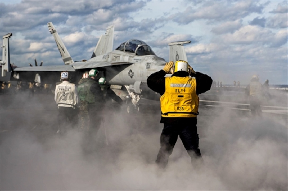 A U.S. sailor directs an F/A-18E Super Hornet into position to launch off the aircraft carrier USS Theodore Roosevelt in the Atlantic Ocean, Jan. 11, 2015. The Roosevelt is participating in a composite unit training exercise. The F/A-18E crew is assigned to Strike Fighter Attack Squadron 211.
