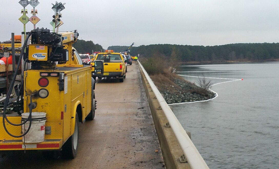 A tractor-trailer overturned on Highway 64 when the driver reportedly lost control on the icy eastbound bridge over Jordan Lake on Wednesday morning, Jan. 14, 2015.  The vehicle did not enter the lake, but came to rest at the water’s edge, according to Jordan Lake Park Ranger Francis Ferrell.  No one was reported injured, but a fuel tank on the vehicle ruptured and 40 gallons of diesel fuel spilled onto the rip-rap and into Jordan Lake.  An unknown amount of crank oil was spilled as well.  North Chatham fire department personnel placed a 600-foot boom around the visible sheen to contain the spill.  Environmental Management officials responded to the scene, and deployed a floating absorbent to mitigate any possible effects from the spill.  Soil and rip-rap containing any contaminants will be removed from the causeway. 