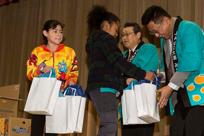 Students from Matthew C. Perry Elementary School present gifts to members of the local Iwakuni agricultural and societal cooperative associations during a mikan presentation inside the school’s gymnasium, Jan. 13, 2015, aboard Marine Corps Air Station Iwakuni, Japan. The purpose of the event was to strengthen the bond between Iwakuni City residents and M.C. Perry Elementary School students. The members of the associations presented M.C. Perry elementary with 20 boxes of mikans from Suo-Oshima Island.