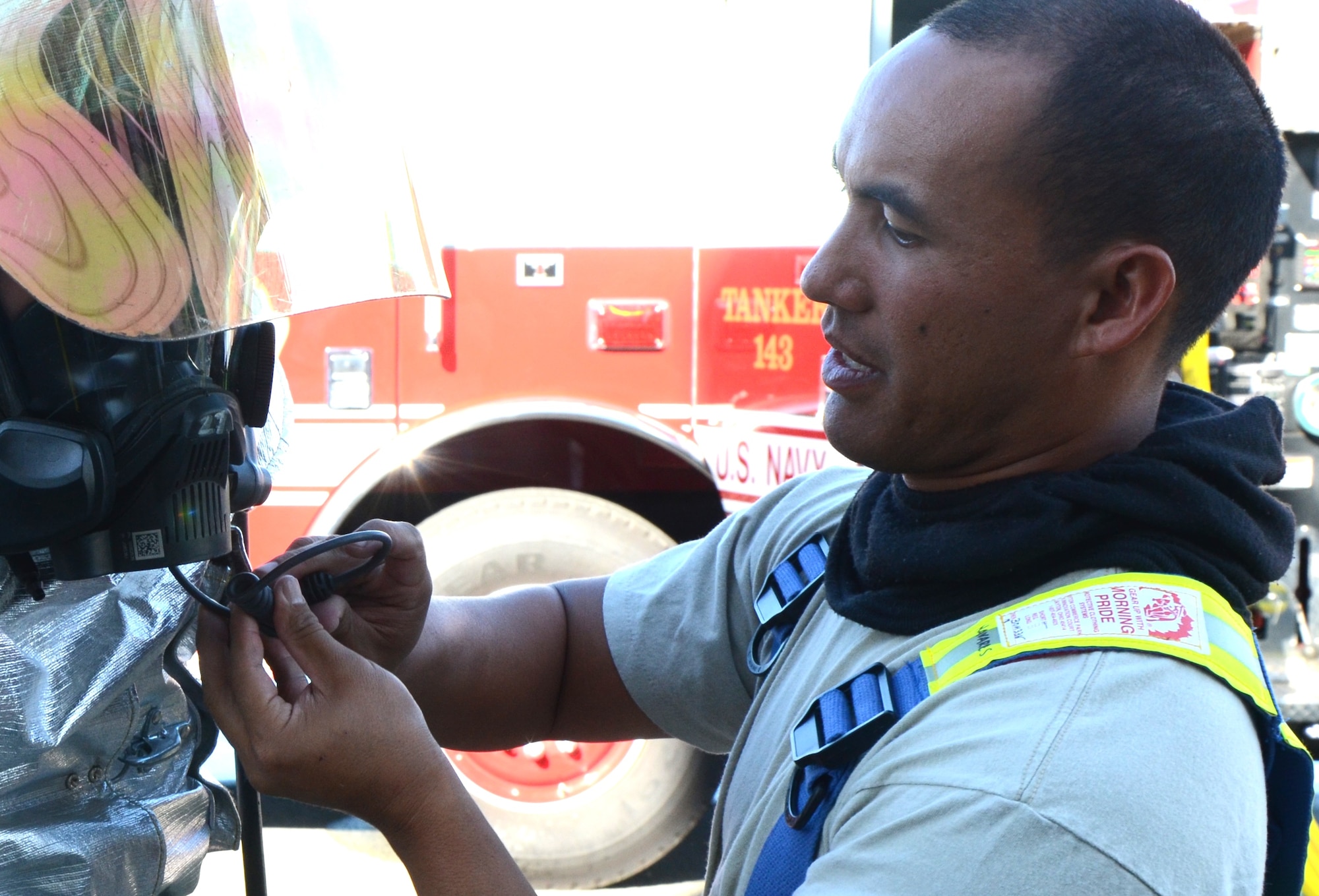 Staff Sgt. Kaina Navares, a firefighter with the 624th Civil Engineering Squadron, adjusts the inhalation connection to a fellow firefighter's air pack--a self-contained breathing apparatus (SCBA)--in preparation for a live-fire training exercise at Hickam Field, Hawai’i, Jan. 10, 2015. The SCBA allows firefighters to remain in adverse conditions for longer time periods. (U.S. Air Force photo by Tech. Sgt. Phyllis Keith)