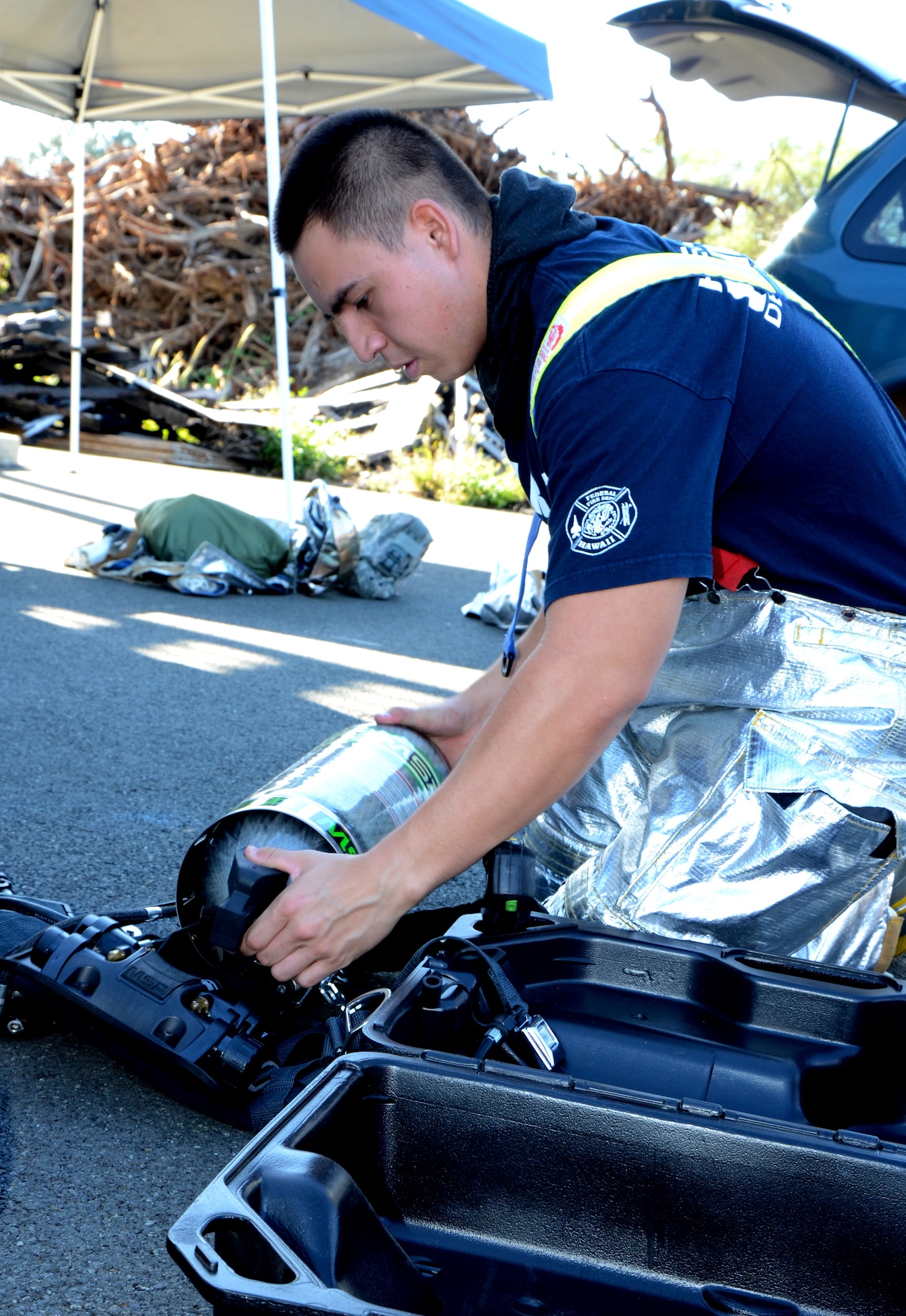 Airman 1st Class Chevy Fonseca, a firefighter with the 624th Civil Engineering Squadron, places his air pack, or self-contained breathing apparatus (SCBA), into its carrying frame in preparation for a live-fire training exercise at Hickam Field, Hawai’i, Jan. 10, 2015. The SCBA is heat and flame resistant, and is designed to reduce the weight penalty on the firefighter.(U.S. Air Force photo by Tech. Sgt. Phyllis Keith)
