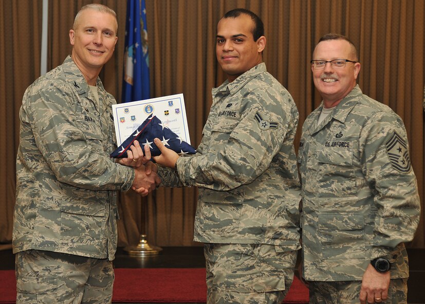 Col. Paul Bauman, 319th Air Base Wing commander, and 319th ABW Command Chief Master Sgt. David Duncan, pose for a photo with Airman 1st Class Herman Longsworth after presenting him with a U.S. flag and certificate of recognition during a wing quarterly awards ceremony held Jan. 15, 2015, at the Northern Lights Club on Grand Forks Air Force Base, N.D. The Airman from the 319th Force Support Squadron was one of six Warriors of the North recognized by the base for becoming naturalized U.S. citizens in 2014. (U.S. Air Force photo/Senior Airman Xavier Navarro)
