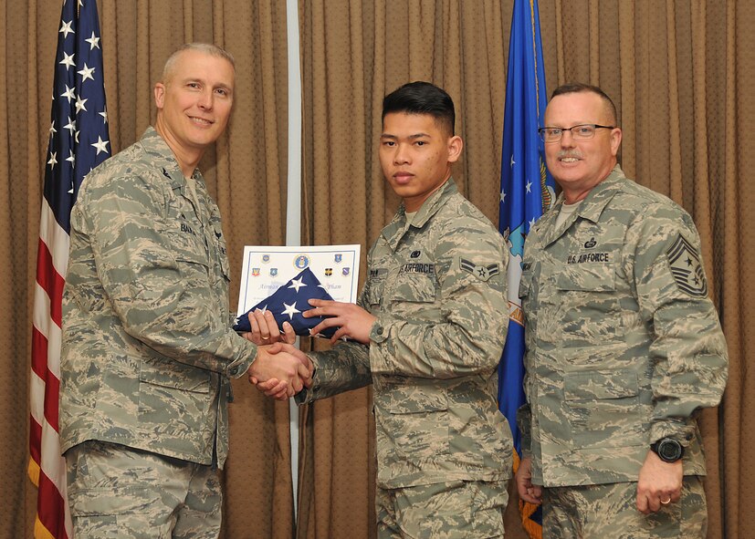 Col. Paul Bauman, 319th Air Base Wing commander, and 319th ABW Command Chief Master Sgt. David Duncan, pose for a photo with Airman 1st Class Danny Pham after presenting the him with a U.S. flag and certificate of recognition during a wing quarterly awards ceremony held Jan. 15, 2015, at the Northern Lights Club on Grand Forks Air Force Base, N.D. The Airman from the 319th Logistics Readiness Squadron was one of six Warriors of the North recognized by the base for becoming naturalized U.S. citizens in 2014. (U.S. Air Force photo/Senior Airman Xavier Navarro)