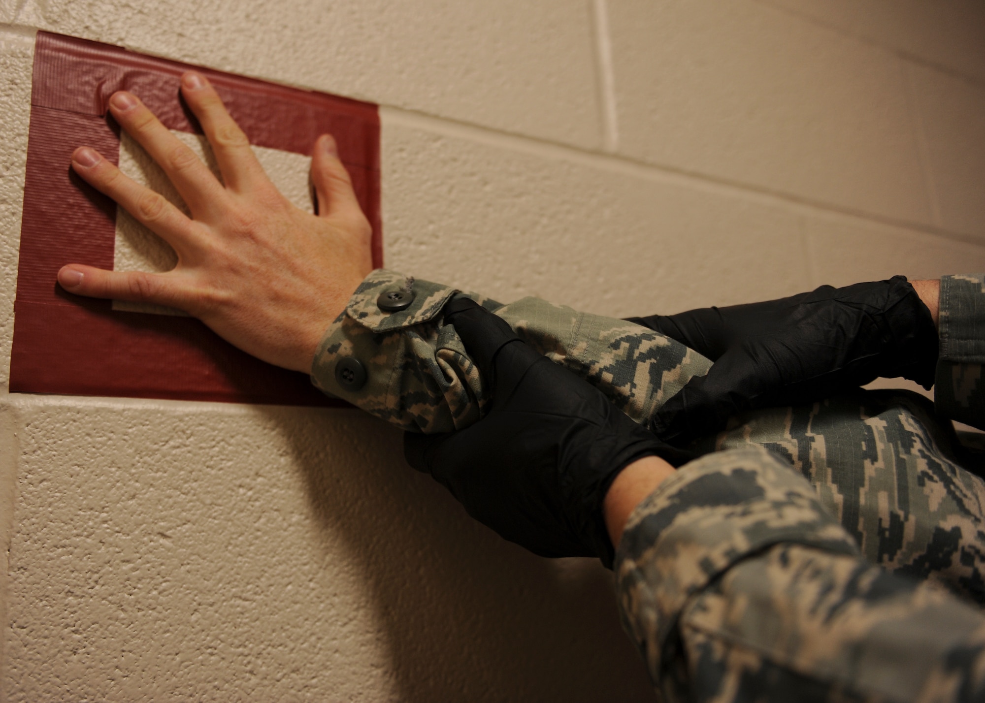 Staff Sgt. Thomas Hodges, the 19th Security Forces Squadron noncommissioned officer-in-charge of confinement, demonstrates the proper procedure for searching an inmate prior to leaving or returning to confinement Jan. 13, 2015, at Little Rock Air Force Base, Ark. Inmates can be held in confinement for a few hours or up to six months at Little Rock AFB. (U.S. Air Force photo by Airman 1st Class Scott Poe)  