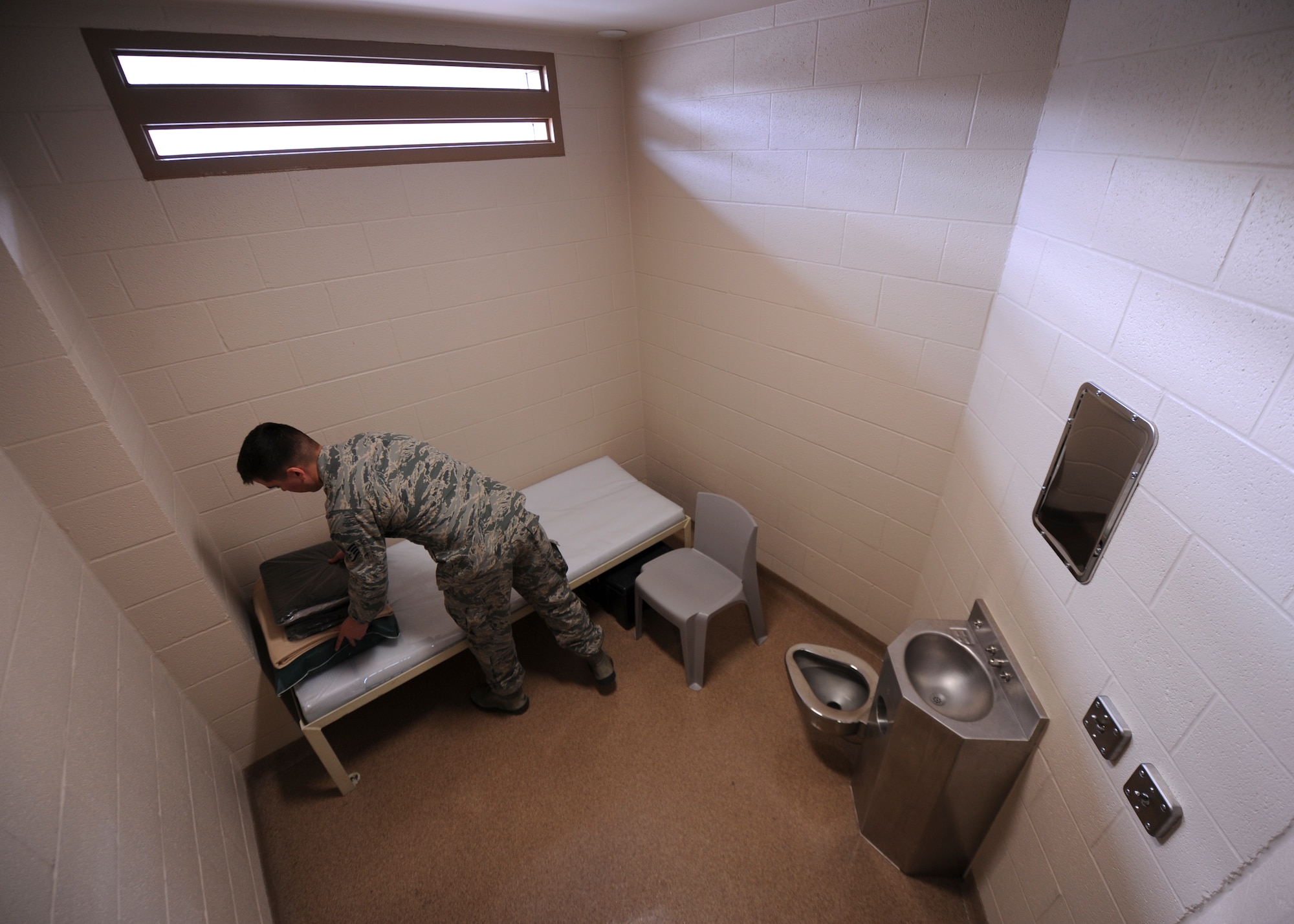 Staff Sgt. Thomas Hodges, the 19th Security Forces Squadron noncommissioned officer-in-charge of confinement, prepares a cell for an incoming inmate Jan. 13, 2015, at Little Rock Air Force Base, Ark. Inmates are normally restricted to their cell during the first 72 hours of being in confinement, except for showers. (U.S. Air Force photo by Airman 1st Class Scott Poe)