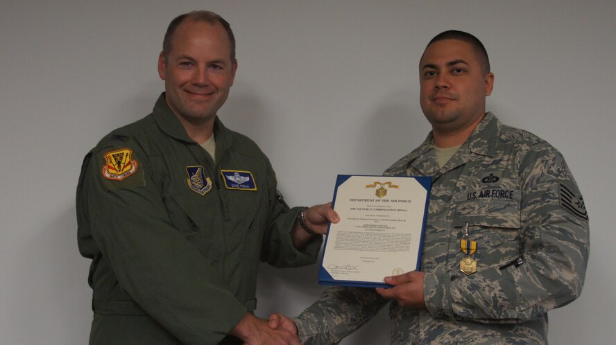 Tech. Sgt. Damian Maldonadorivera Jr., a command post controller for the 154th Wing Control Center, receives the Air Force Commendation Medal from Air Force Col. Duke Pirak, acting vice commander of the 154th Wing, Hawaii Air National Guard. Maldonadorivera received the award for outstanding service in the Hawaii Air National Guard during a commander's call at Joint Base Pearl Harbor-Hickam, Hawaii, Jan. 11, 2015. (Hawaii Air National Guard Photo/Tech. Sgt. Andrew Jackson)