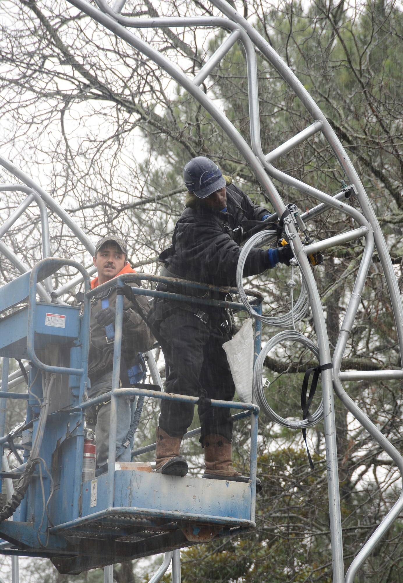 Casey Ramirez(left) and Fred Florence, technical representatives for a Florida contractor, help assemble a canopy at the truck gate, January 13, 2015. (U.S. Air Force photo by Ed Aspera)