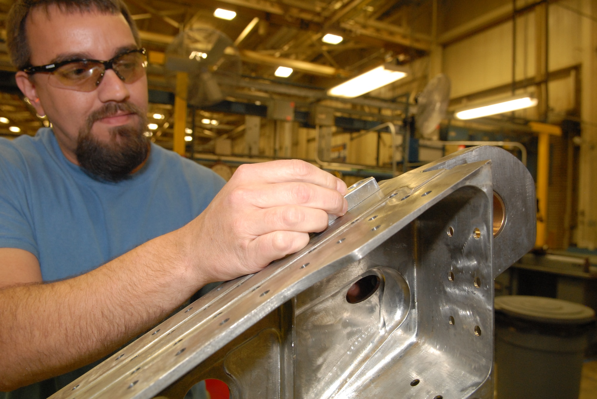 Josh Bryant, a machinist with the 573rd Commodities Maintenance Group, demonstrates equipment used to drill precise measurements to remove a crack from an F-15 wing spar. (U.S. Air Force photo by Misuzu Allen)