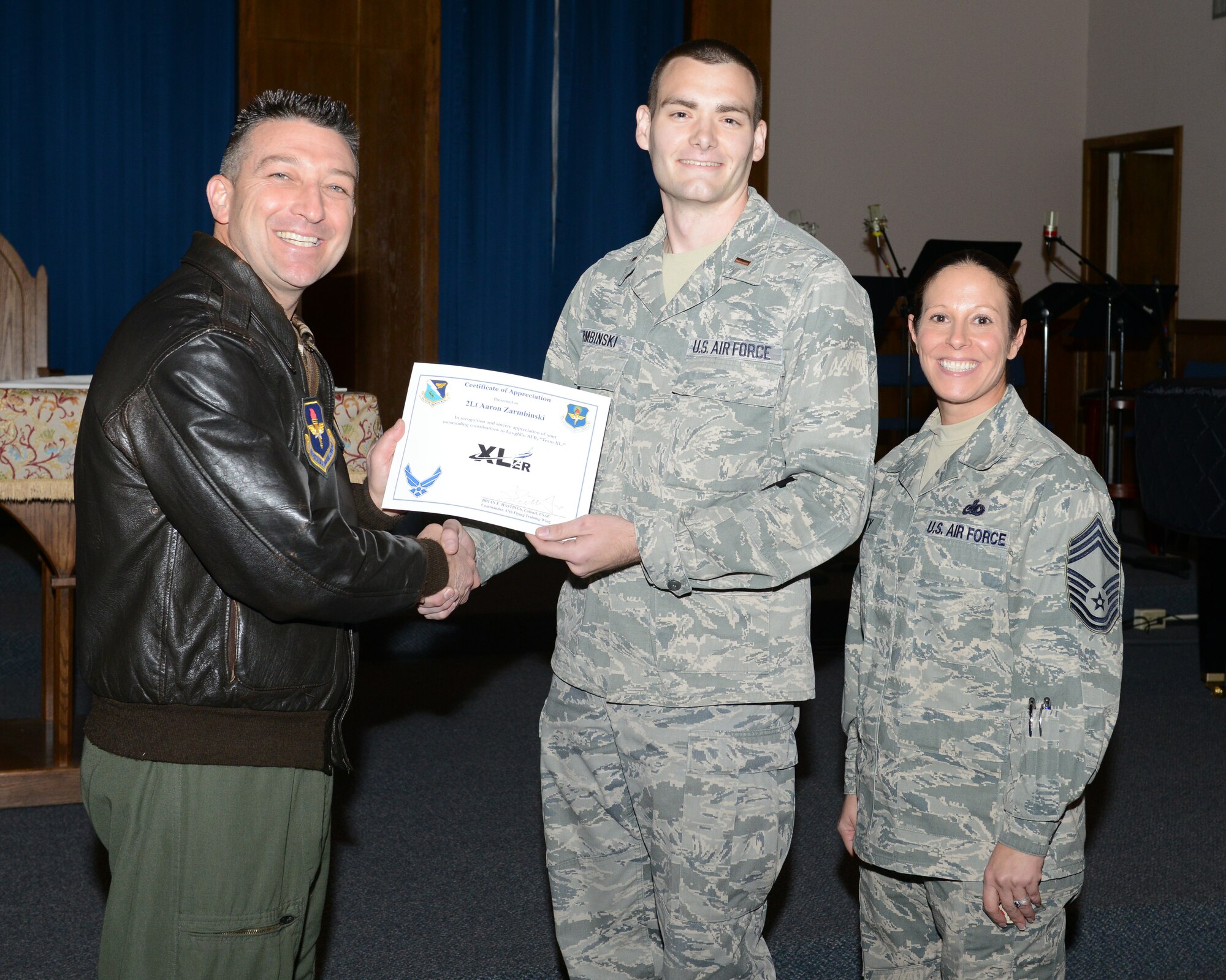 Second Lt. Aaron Zarmbinski, center, 47th Student Squadron awaiting pilot training, poses with Col. Brian Hastings, left, 47th Flying Training Wing commander, and Chief Master Sgt. Patricia Hickey, right, 47th Mission Support Group command chief, after accepting the XLer of the week award here Jan. 14, 2015. The XLer is a weekly award chosen by wing leadership and is presented to those who consistently make outstanding contributions to their unit and Laughlin. (U.S. Air Force photo by Airman 1st Class Jimmie D. Pike)(Released)