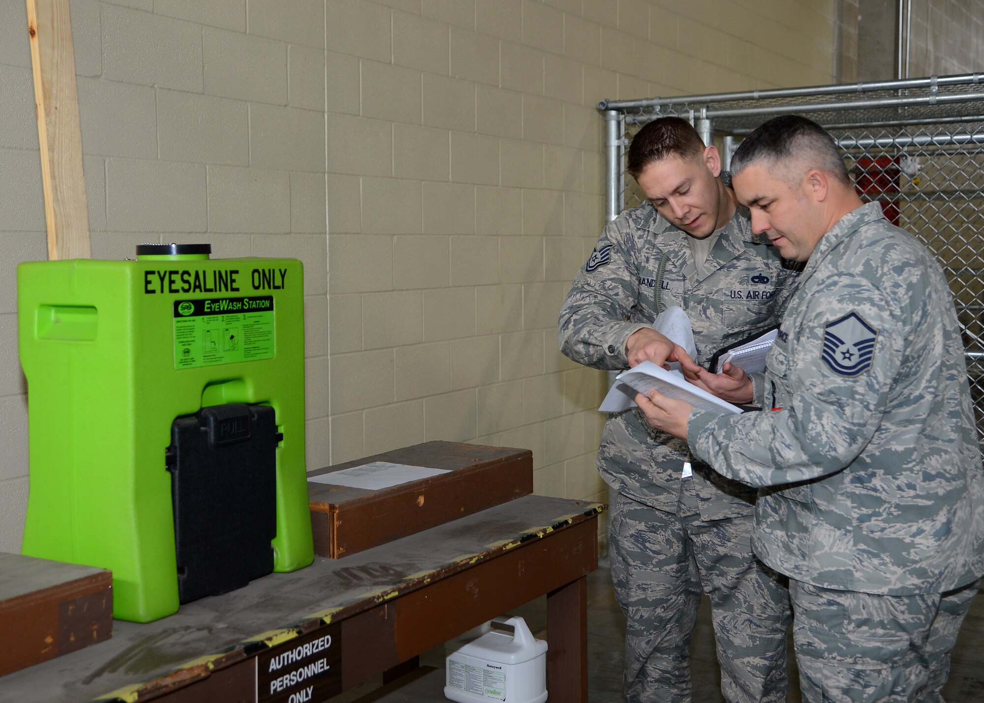 Tech. Sgt. Alexander Crandall, 2nd Maintenance Group, and Master Sgt. Theison, 2nd Munitions Squadron, 2nd Bomb Wing Inspection Team members, check the maintenance schedule from an eyewash station at the 2nd Logistics Readiness Squadron on Barksdale Air Force Base, La., Jan. 12, 2015. WIT volunteers were tasked with reviewing Air Force instructions, asking questions based on squadron checklists, their own self-inspection checklists and also from topics directed from the 2nd LRS commander. (U.S. Air Force photo/Senior Airman Joseph A. Pagán Jr.)