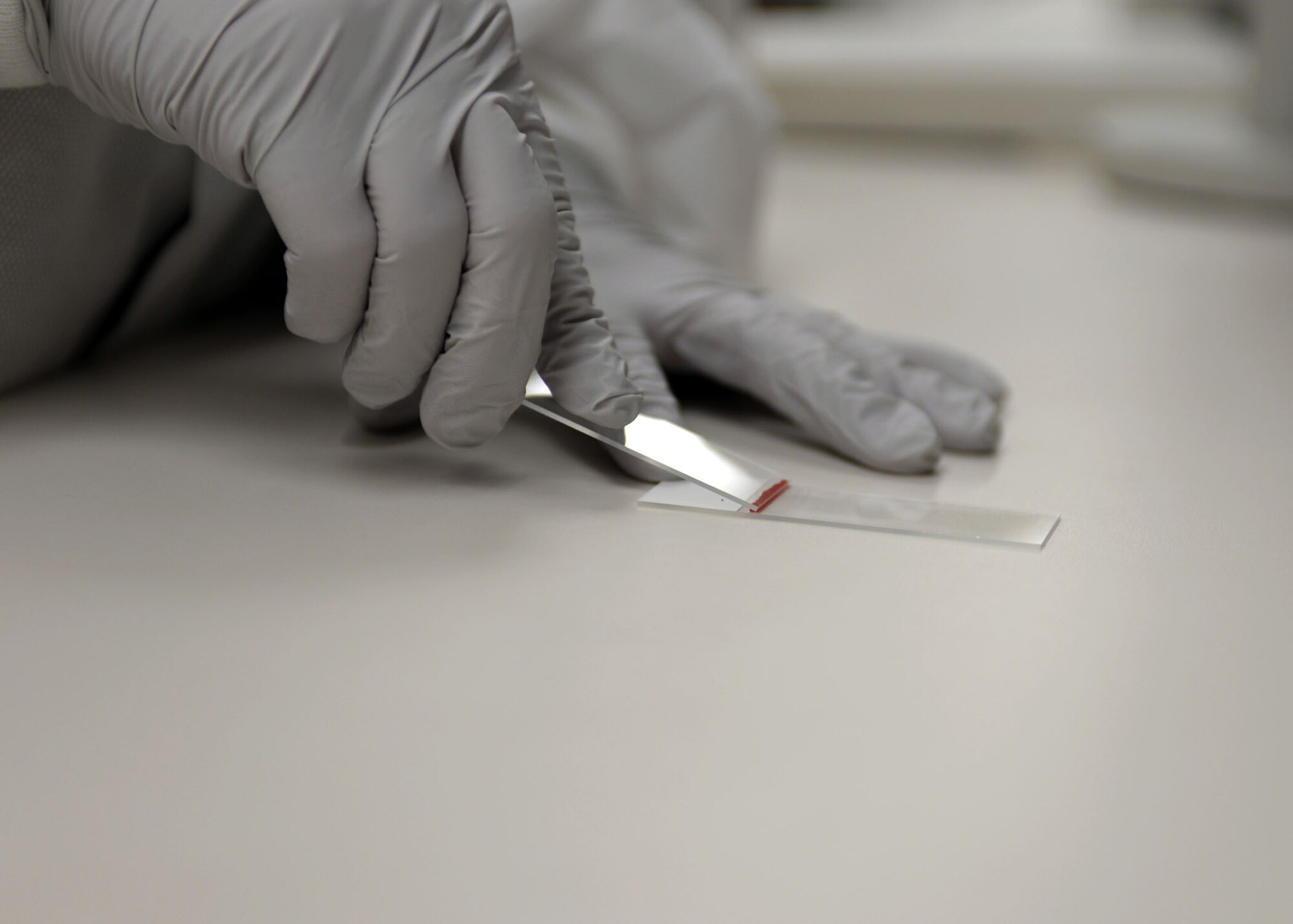 ALTUS AIR FORCE BASE, Okla. – U.S. Air Force Tech. Sgt. Kristi Jordan, 97th Medical Support Squadron NCO in charge of laboratory service, spreads a blood sample at the laboratory, Jan. 13, 2015. The 97th Medical Support Squadron Laboratory conducts specific test which can help determine if an individual is ill. (U.S. Air Force photo by Senior Airman Franklin R. Ramos/Released)