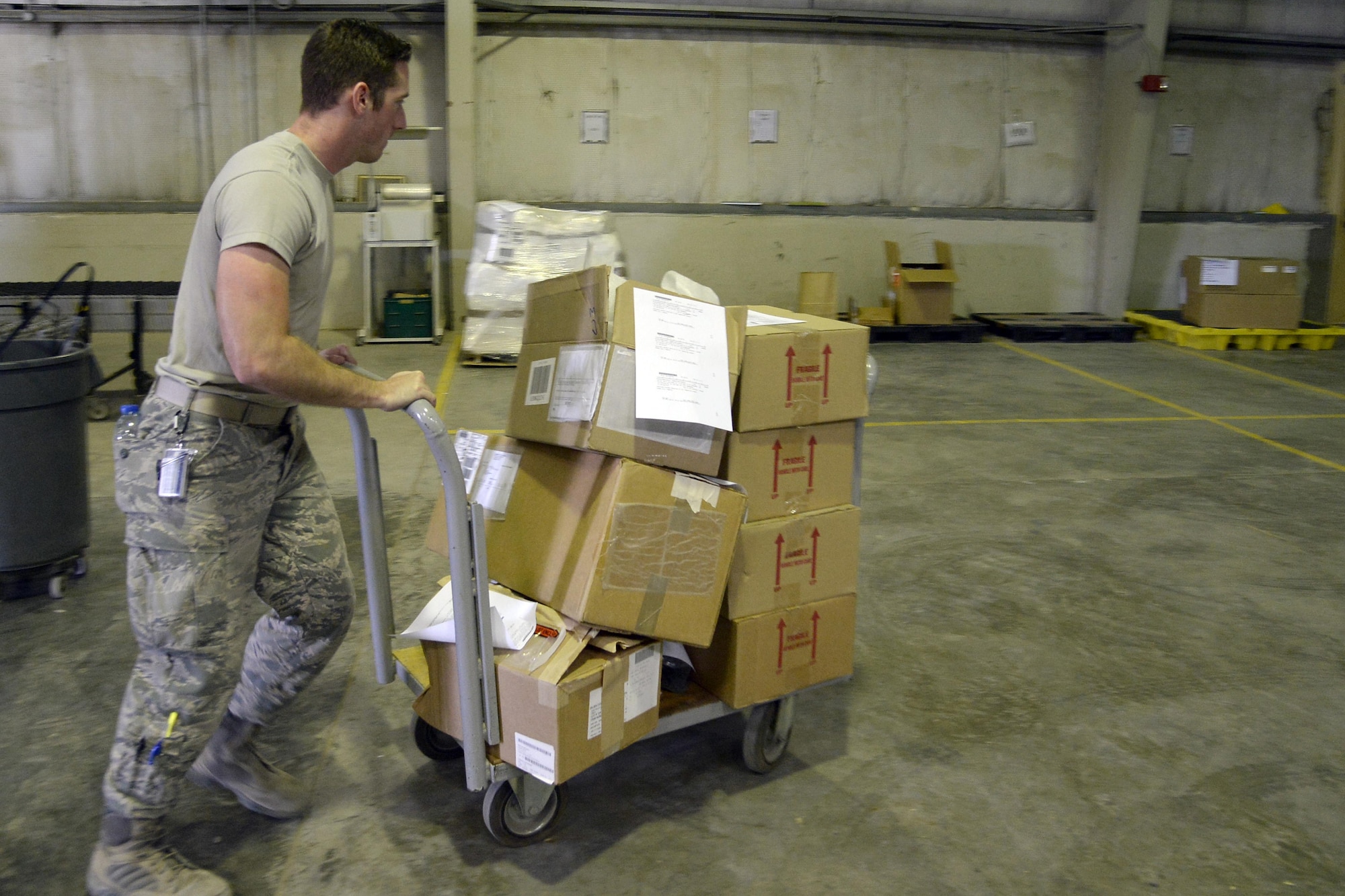 Airman 1st Class Benjamin, inbound cargo journeyman, pushes cargo to the staging area at an undisclosed location in Southwest Asia Jan. 13, 2015. TMO personnel have to work aggressively to contact customers to pick up their cargo before the assets go delinquent, which occurs six days after receipt of the asset. Benjamin is currently deployed from Luke Air Force Base, Ariz., and is a native of Houston, Texas. (U.S. Air Force photo/Tech. Sgt. Marie Brown)