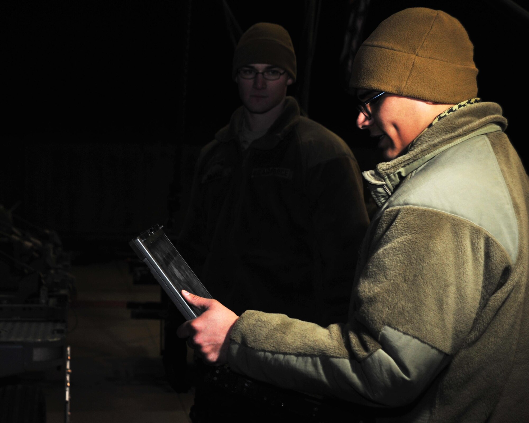 U.S. Air Force Airman 1st Class Vincent Martinez and U.S. Air Force Airman 1st Class Jared Moore, 455th Expeditionary Maintenance Squadron line delivery crew members, read Technical Orders in preparation for a munitions transportation mission Jan. 14, 2015 at Bagram Airfield, Afghanistan. Line delivery Airmen have completed 741 munitions deliveries since October, ensuring the timely facilitation of airpower to the U.S. Central Command area of responsibility. (U.S. Air Force photo by Staff Sgt. Whitney Amstutz/released)