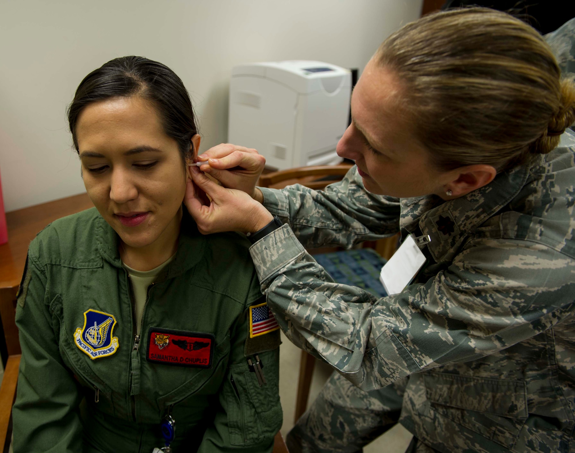Maj. Katie Crowder, 15th Medical Group Family Health Clinic medical director, demonstrates the correct technique for battlefield acupuncture on Maj. Samantha Chuplis, 535th Airlift Squadron flight surgeon, during a refresher course for battlefield acupuncture at the 15th MDG at Joint Base Pearl Harbor-Hickam, Hawaii, Jan. 15, 2015. During the procedure up to five gold semi-permanent needles are placed into each ear. (U.S. Air Force photo by Tech. Sgt. Terri Paden)