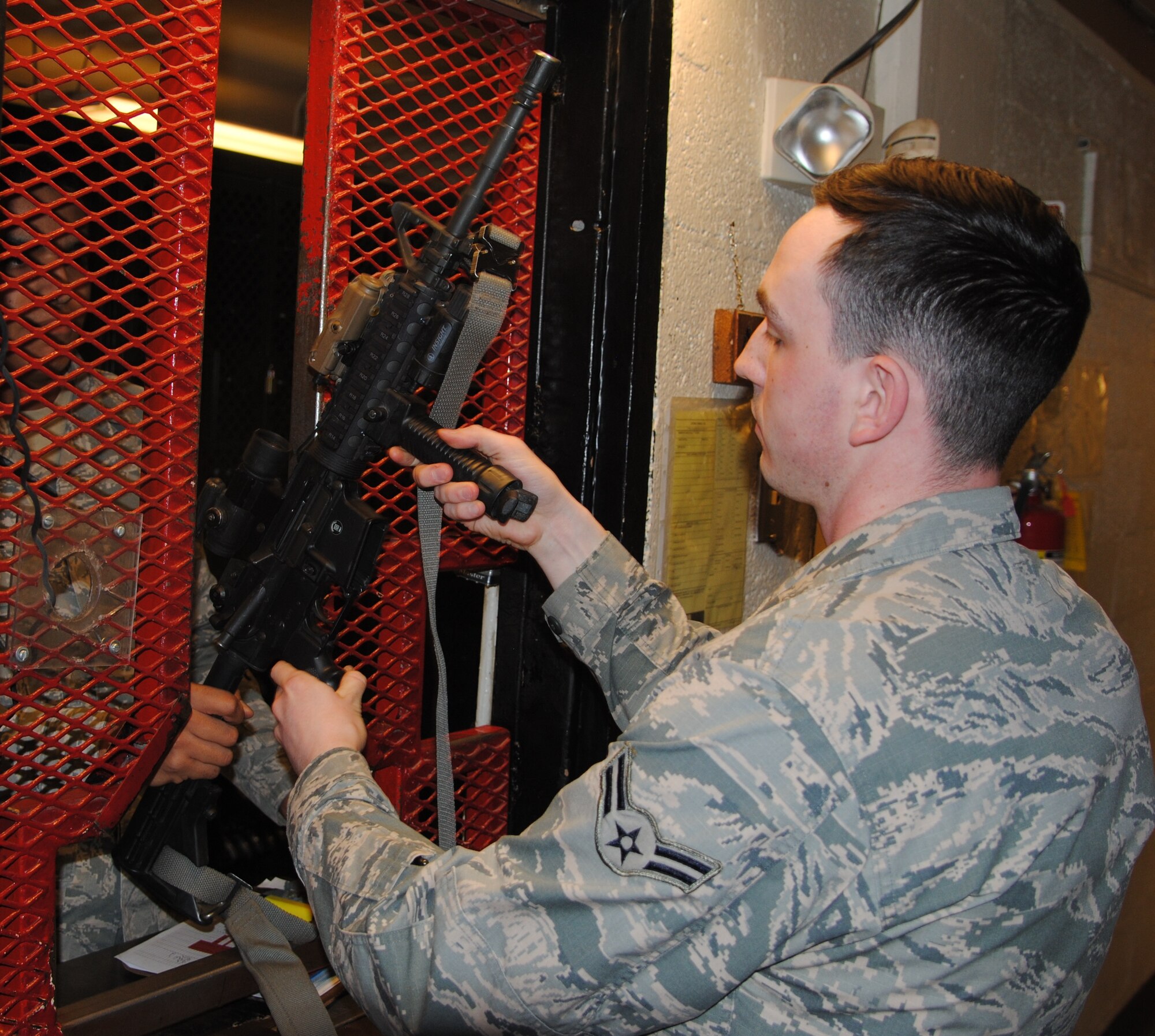 Airman 1st Class Travis White returns his duty weapon, an M-4, do the Security Forces Armory and Armerer Airman 1st Class Levi Savage checks it back in. Dorm residents must store authorized weapons in the armory. (Photo by Jim Fisher)