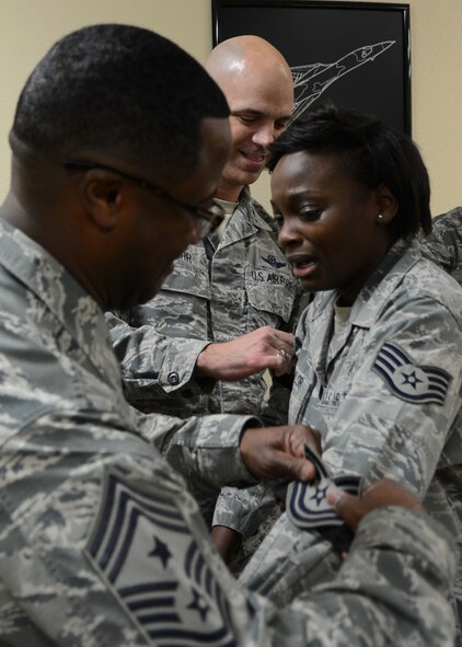 U.S. Air Force Col. Michael Bob Starr, 7th Bomb Wing commander, and Chief Master Sgt. Eddie Webb, 7th Bomb Wing command chief, put new technical sergeant stripes on Tech. Sgt. Raven Taylor, 7th Medical Operations Squadron medical technician, Dec. 22, 2014, at Dyess Air Force Base, Texas. Starr and Webb surprised Taylor during a squadron staff meeting where she was notified of her Stripes for Exceptional Performers promotion. (U.S. Air Force photo by Airman 1st Class Kedesha Pennant/Released)