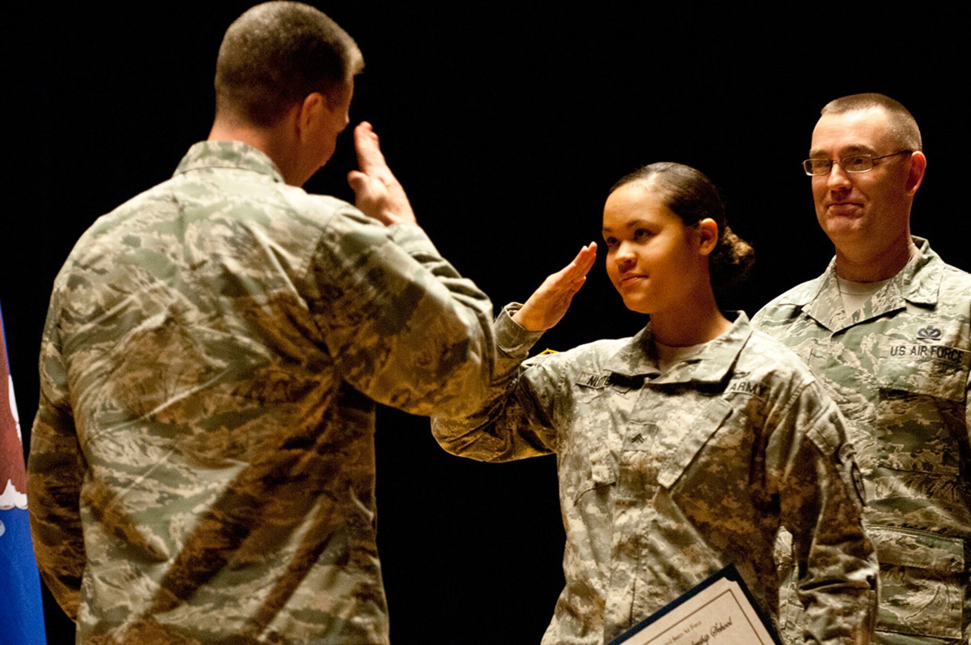 Corporal Janay Nutter, a radio retransmission squad leader with C Company, 6th Brigade Engineer Battalion, 4th Infantry Brigade Combat Team (Airborne), 25th Infantry Division, salutes Air Force Col. Brian Bruckbauer, commander of JBER and the 673rd Air Base Wing, during the Airman Leadership School graduation at Talkeetna Theater at Joint Base Elmendorf-Richardson Dec. 18. (U.S. Army photo/Staff Sgt. Daniel Love)